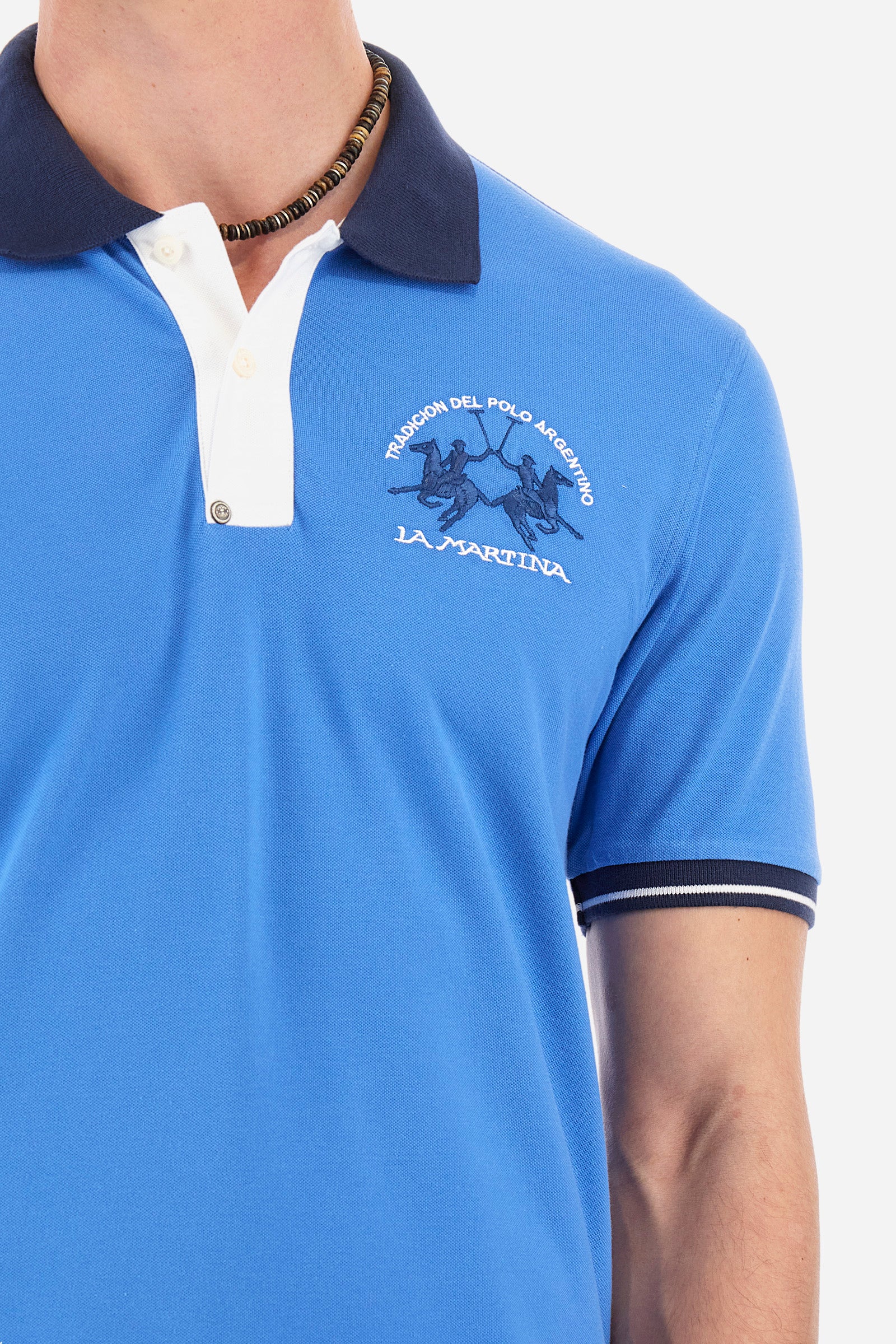 Men's single-colour short-sleeved polo in elasticated cotton. Fastens with two contrasting buttons. Ribbed collar and armholes in different shades. The "La Martina" lettering can be found under the collar. A large logo is embroidered on the chest. The fit is slim. The model wears a size L. - Campanula