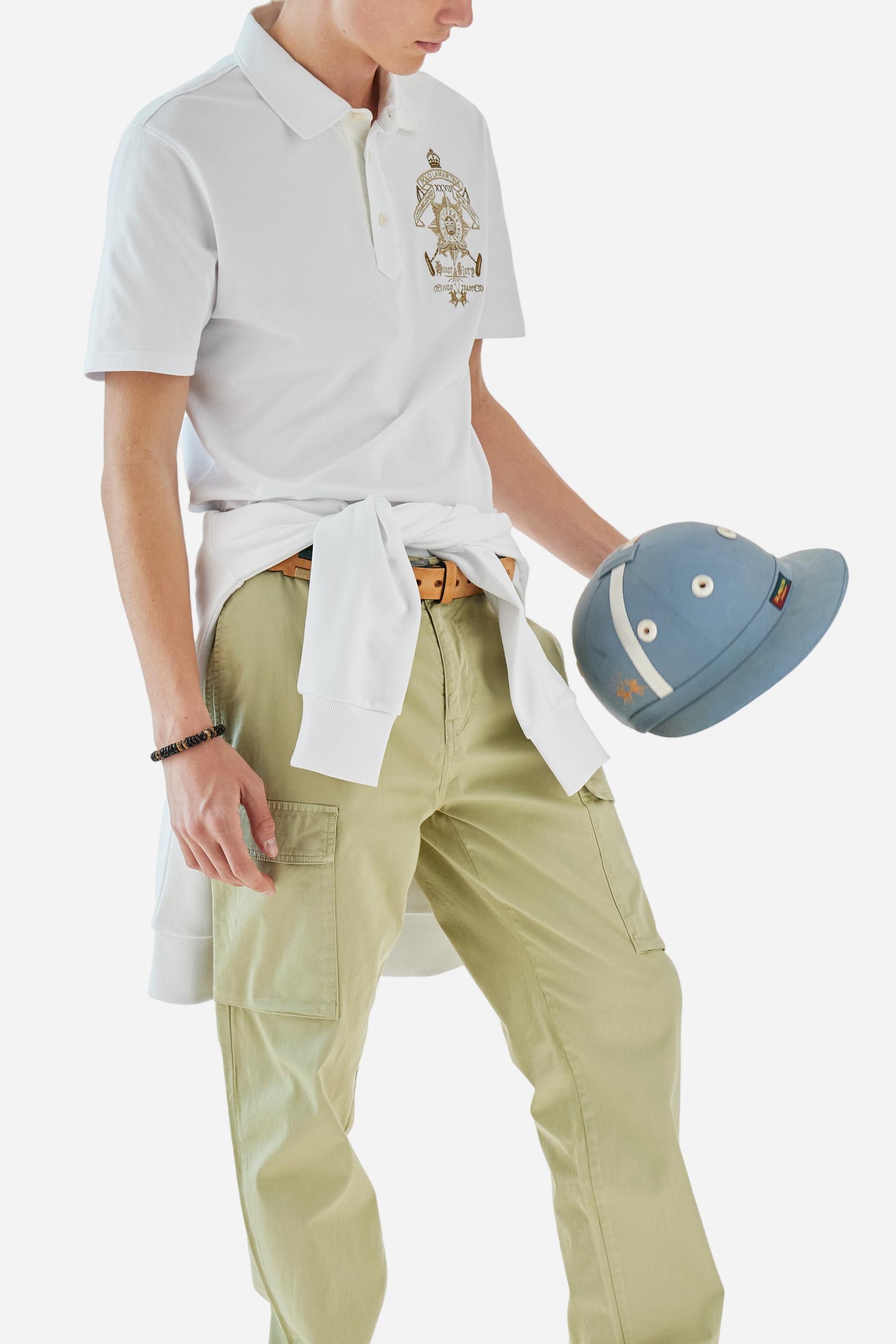 Men's short-sleeved Guards polo shirt in a single colour, made of stretch pique cotton. Fastens with three customised natural faux mother-of-pearl buttons. On the left side of the chest there is a large colour-contrasting embroidery motif, representing the Guard Polo Club. Colour-contrasting tag sewn on the back of the collar. The logo is embroidered on the front. Regular fit. The model is wearing a size L. - Optic White