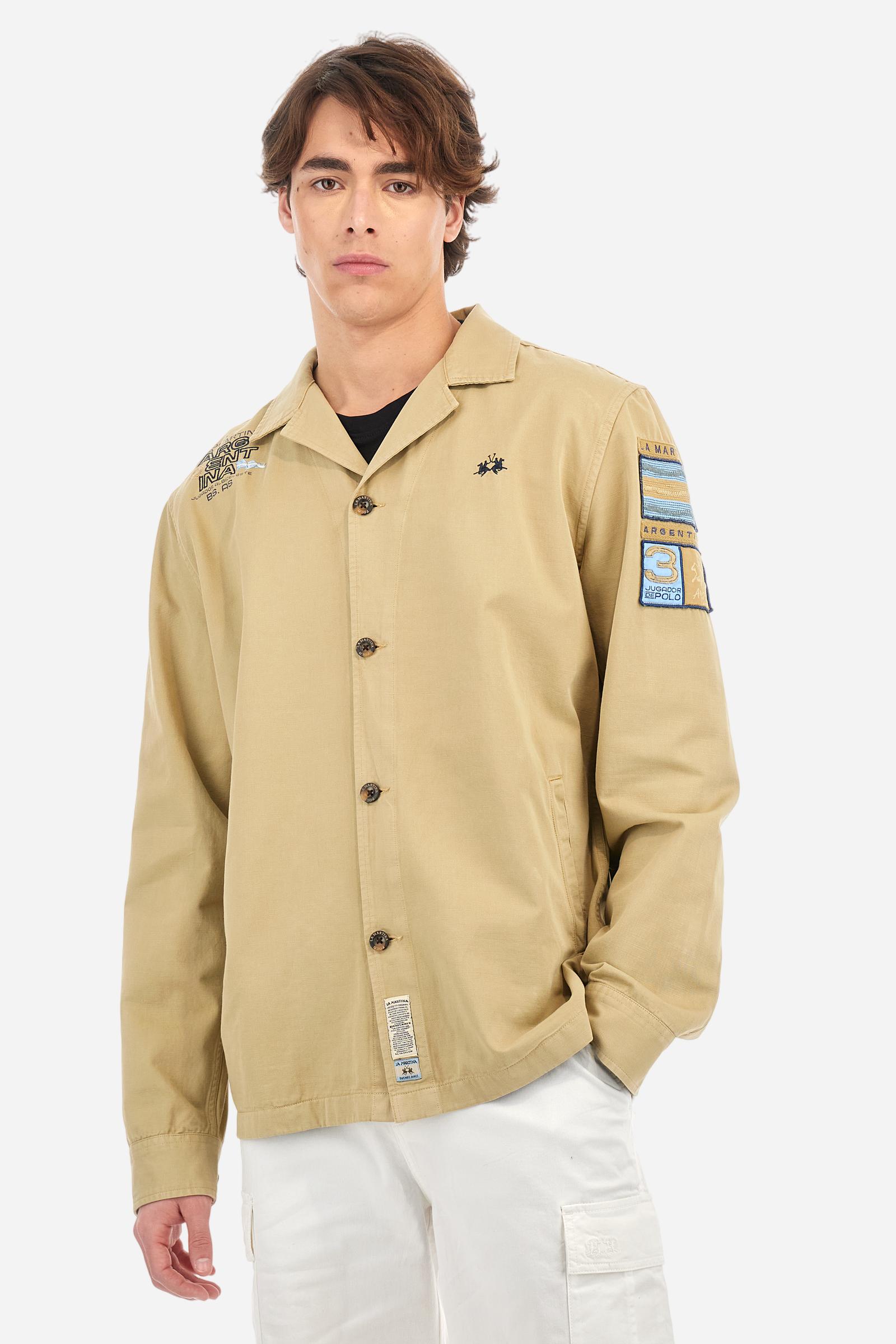 Men's single-colour long-sleeved overshirt made of 100% cotton slub twill. Bowling collar and jacket opening with inside placket, fastening with imitation horn buttons.On the shoulder and chest the embroidery is in tone with the garment, Argentina lettering embroidered on one shoulder. There are several patches applied on the left sleeve. A tone-on-tone logo is embroidered on the front. Regular fit. The model is wearing a size L. - Twill