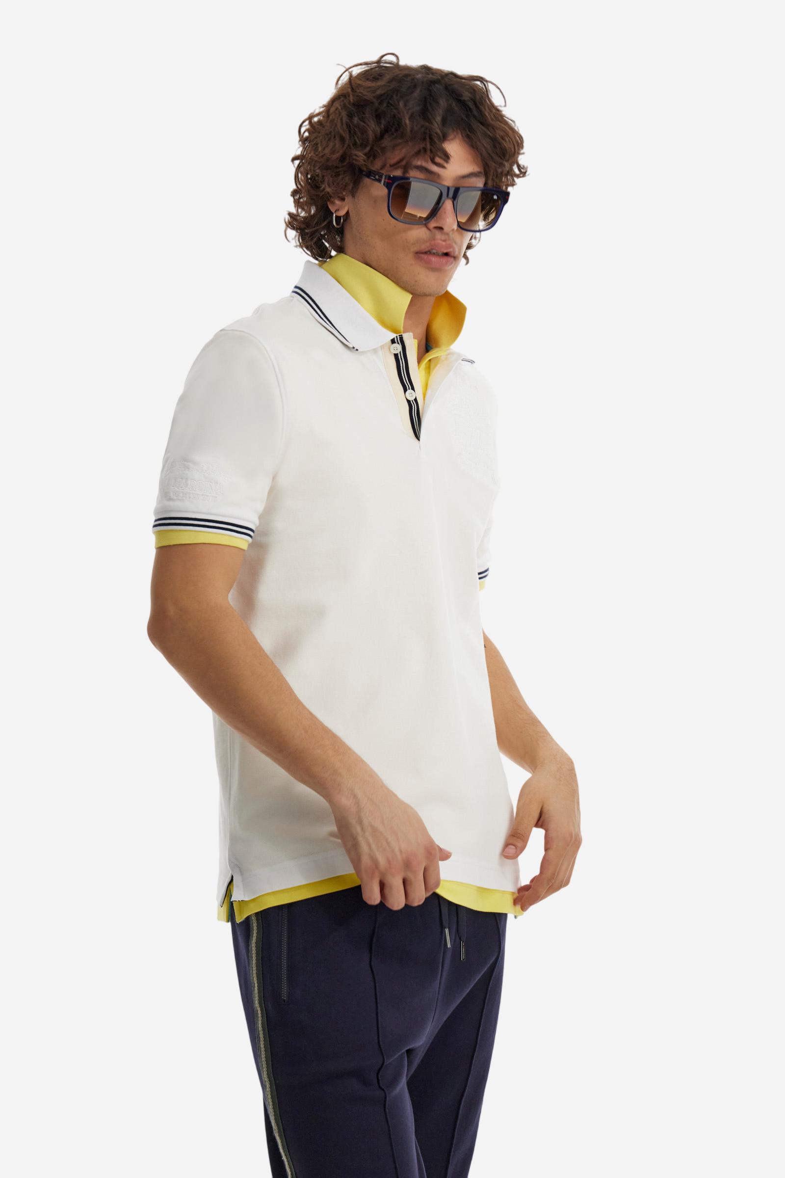 Men's plain short-sleeved polo shirt made from stretch piqué. Two-button fastening. The collar and cuffs are made from two-tone striped ribbed fabric. The inside of the collar and placket feature contrasting fabrics and colours. There is a two-tone striped band around the inside of the collar. The right sleeve and chest are embroidered in tone-on-tone thread. A logo is embroidered on the left sleeve, also using tone-on-tone thread. Regular fit. The model is wearing a size L. - Optic White