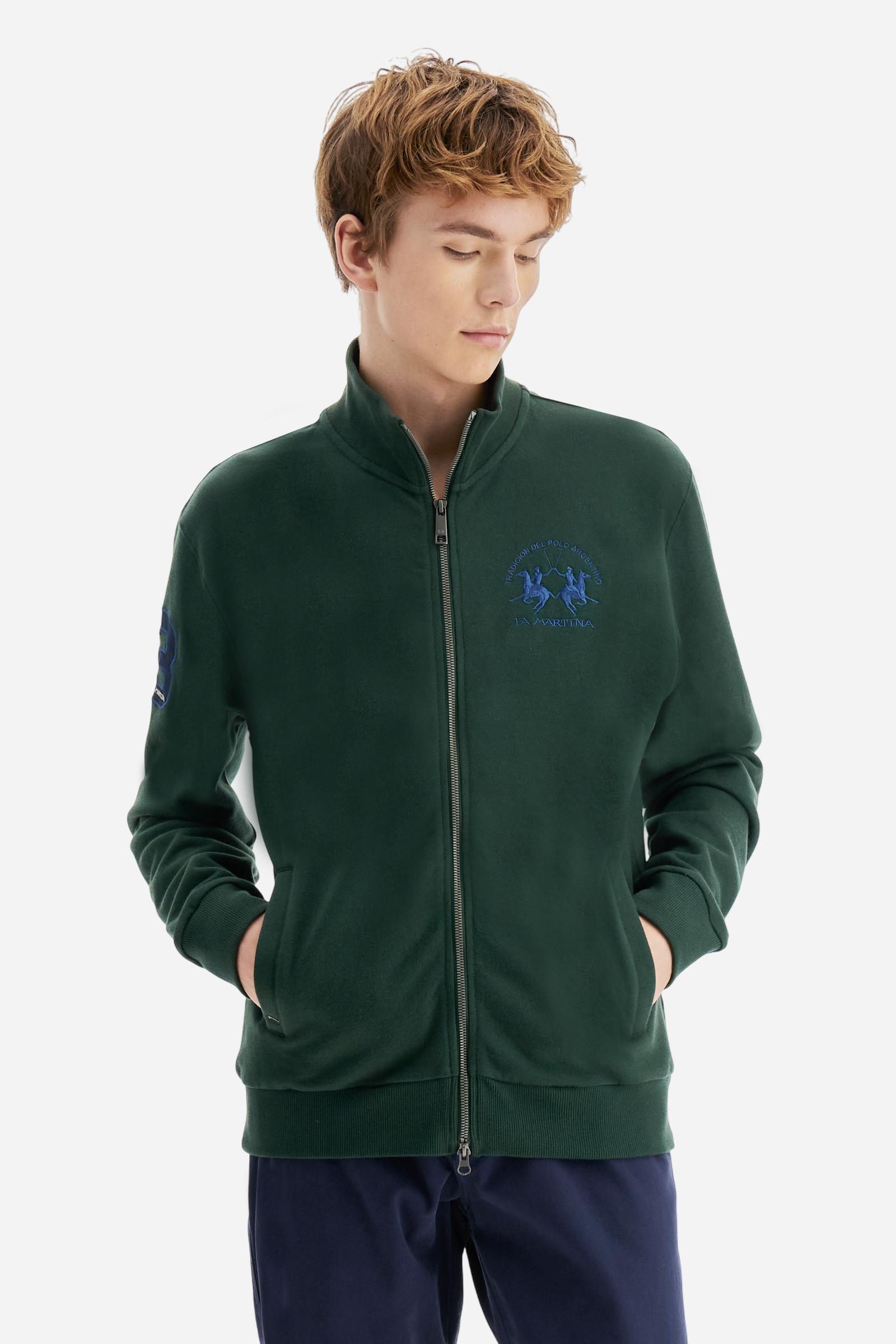 Men's long-sleeved solid colour sweatshirt. It is made of comfortable 100% cotton fleece with a soft-brushed feel. Model with high ribbed neck and front zip opening. Solid colour ribbed cuffs and waistband. The large contrasting brand team logo is embroidered on the chest. A contrasting colour fabric number patch is applied to the right sleeve. The model has a regular fit that offers a comfortable, relaxed silhouette. The model is wearing a size L. - Sycamore