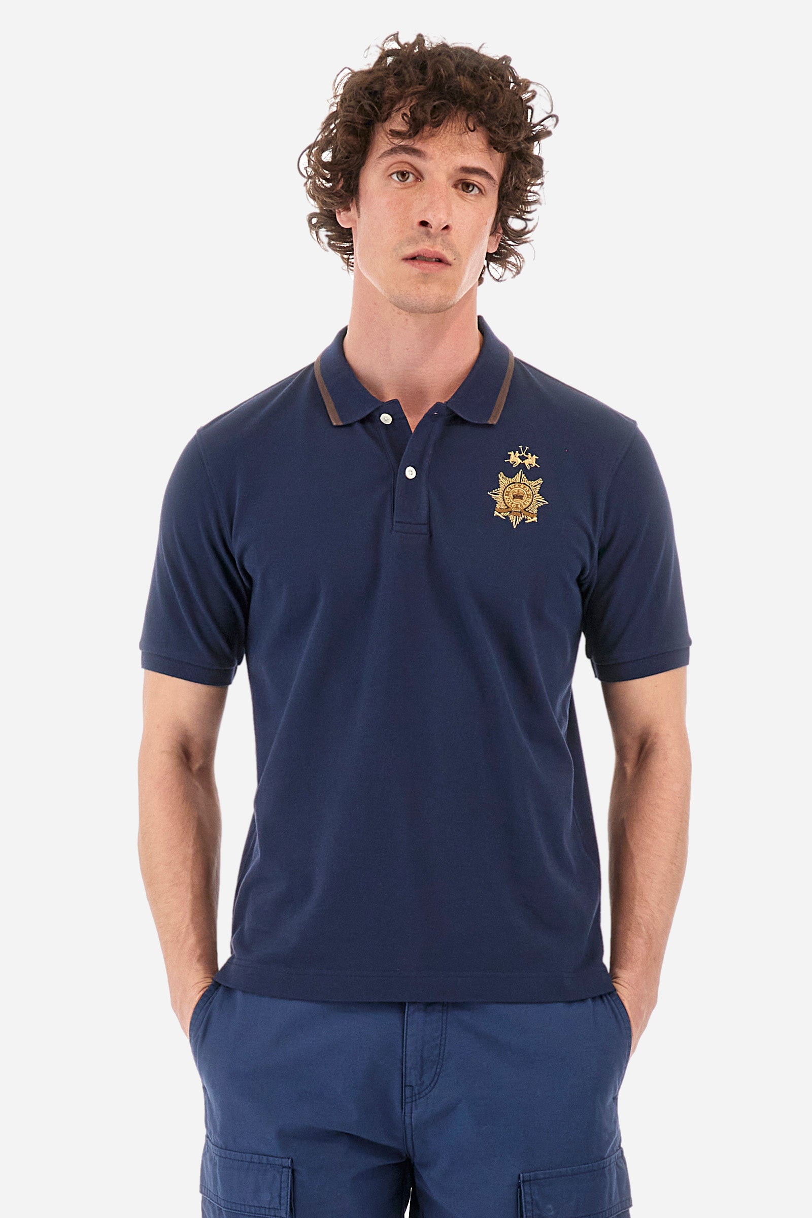 Men's short-sleeved single-colour polo shirt in elasticated cotton. Two-button fastening. Ribbed collar and armholes. The neck is profiled. On the front we find the symbol representing the Guards line. Featuring a small logo embroidered on the chest. The fit is regular. The model wears a size L. - Navy