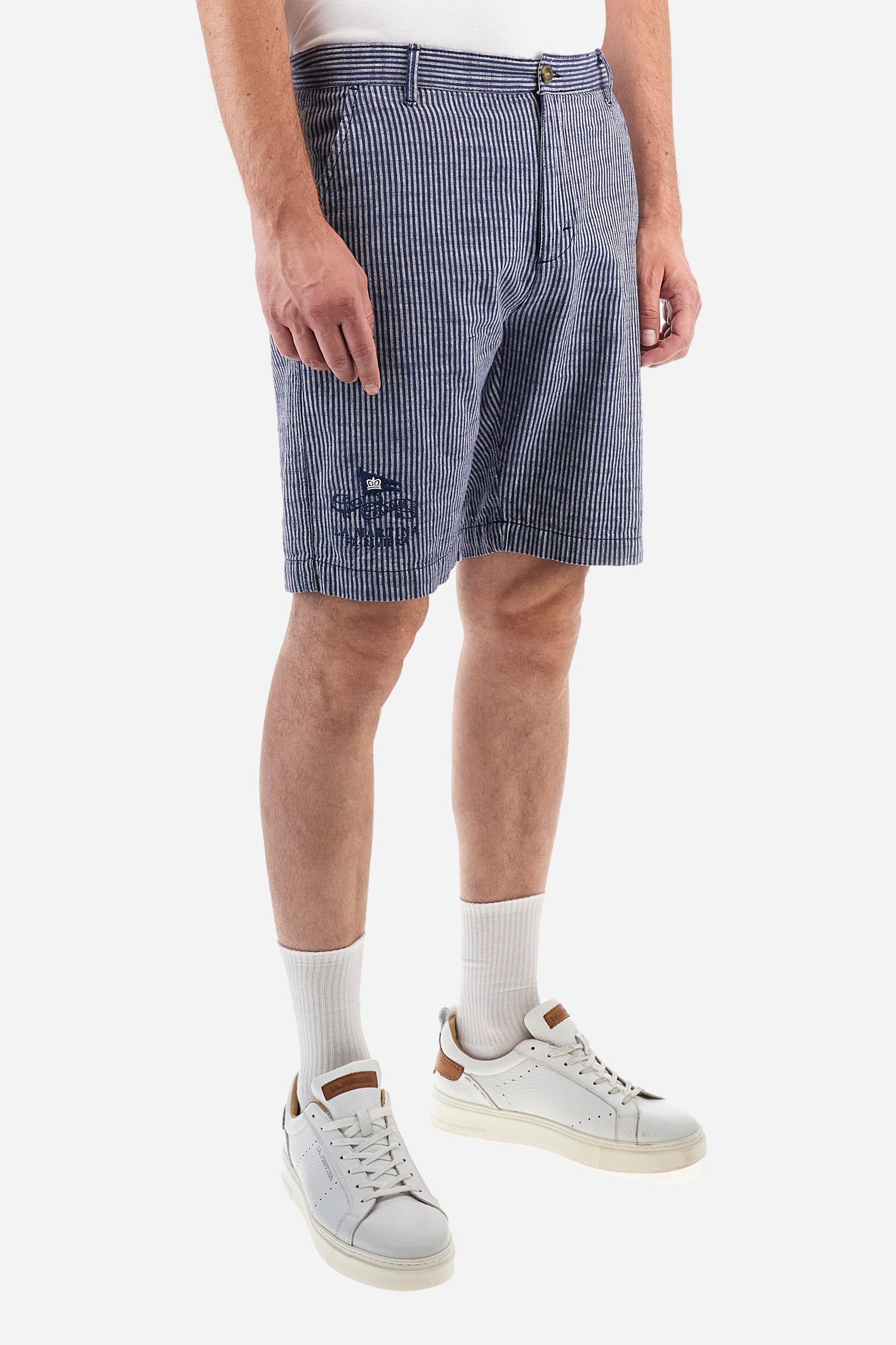 Striped men's Bermuda shorts made from luxurious cotton and linen canvas. Fastened with a zip and faux horn button. The side pockets are slanted, while the double welt back pockets are feature visible faux horn buttons and double-needle stitching around the edges. Above the right back pocket, a woven label explains the brand's quality certification. On the right hem, a graphic reading La Martina is embroidered in colourful thread. Regular fit. The model is wearing a size L. - EnsignBlue/Opt.White