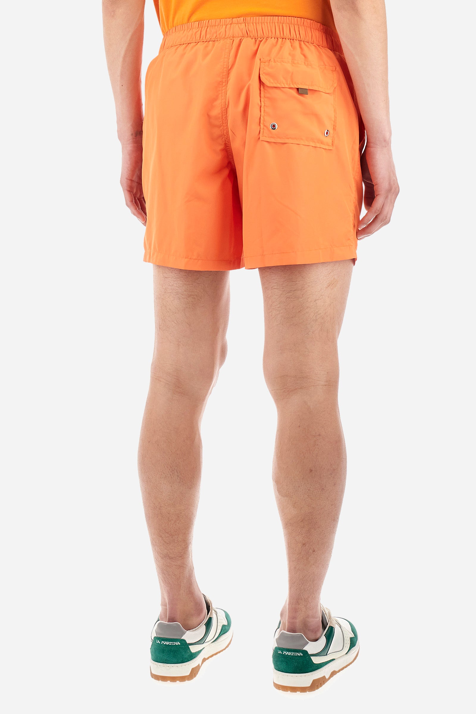 Single-colour men's swimming shorts, made of synthetic fabric. Featuring a drawstring and tie with "La Martina" lettering. Double welt pocket on the front. Closed pocket on the back. Mesh lining. Large logo embroidered on the front. The fit is regular. The model wears a size L. - Celosia Orange