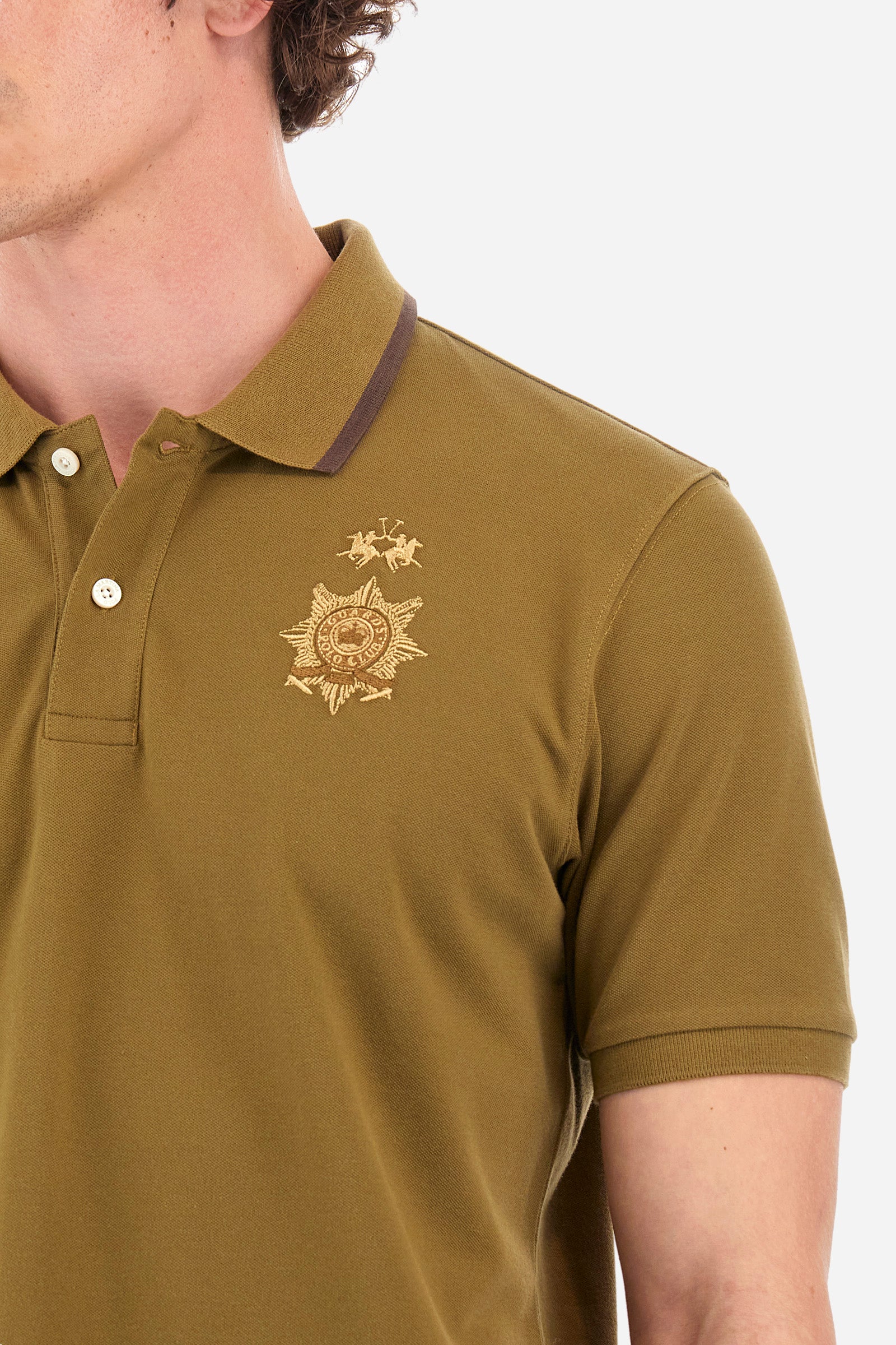 Men's short-sleeved single-colour polo shirt in elasticated cotton. Two-button fastening. Ribbed collar and armholes. The neck is profiled. On the front we find the symbol representing the Guards line. Featuring a small logo embroidered on the chest. The fit is regular. The model wears a size L. - Military Olive