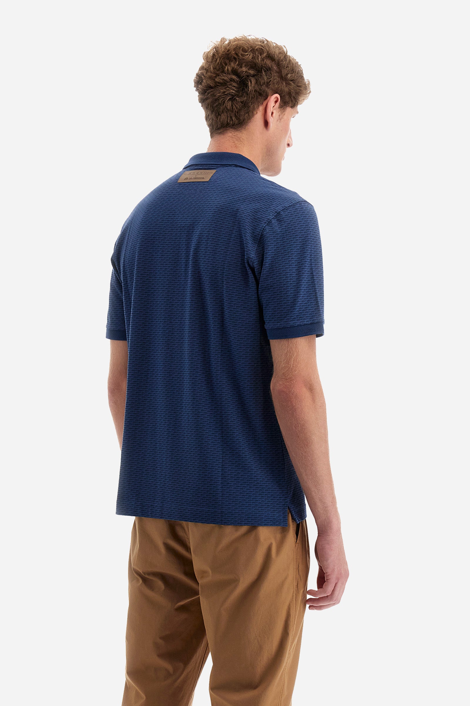 Single-colour men's polo shirt with short sleeves from the line in collaboration with Pagani. Made of stretch cotton. Two-button fastening. The collar and armholes feature a different texture. The garment features lettering throughout. A patch with the brand's name and logo and the word "Pagani" is applied on the back. The fit is regular. The model wears a size L. - ENSIGNBLUE/NAVYBLAZE