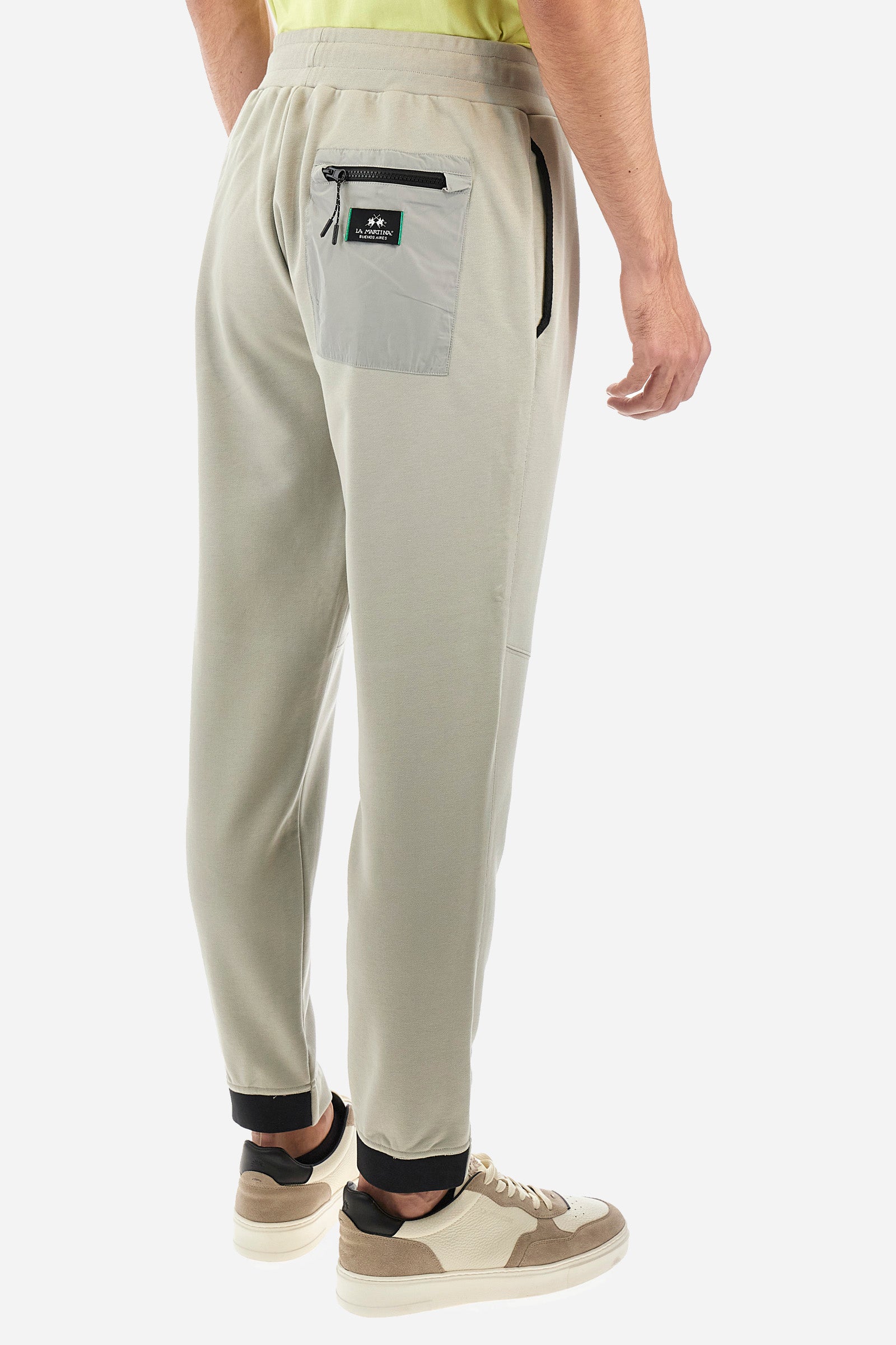 Men's single-colour jogging bottoms in a cotton sweat fabric. With a drawstring waist and double front pocket. With different shades at the bottom of the leg. On the back there is a pocket with a zip fastening featuring contrasting textures and colours. The logo is present on the tag sewn on the back pocket. The fit is regular. The model wears a size L. - Pussywillow Grey
