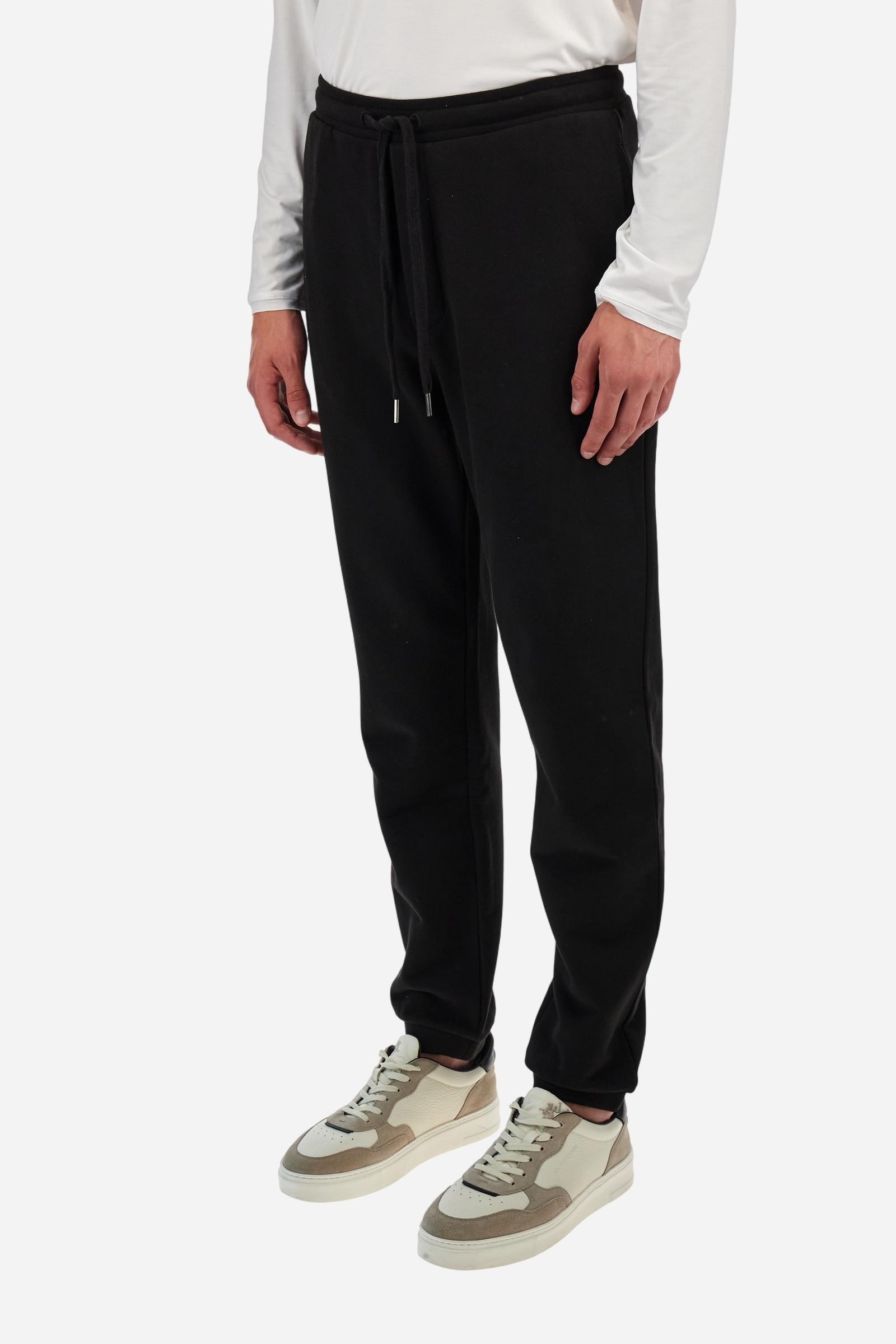 Single-colour men's jogging trousers in a French terry cotton sweat fabric. Removable and adjustable waistband with drawstring. American pockets at the sides. An additional patch pocket is applied on the back. The logo is embroidered in a colour-contrasting thread on the front, left side. The fit is regular. The model is wearing a size L. - Black