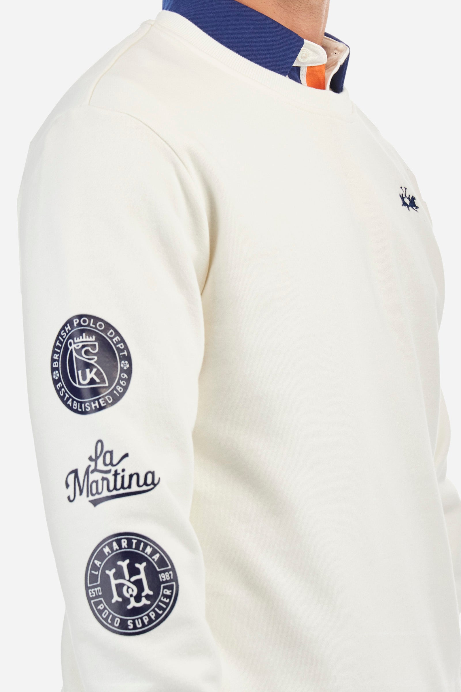 Men's long-sleeved crew neck sweatshirt, made from plain 100% cotton. Ribbed hem, neckline and cuffs. One of the sleeves is finished with symbols and the words La Martina. The logo is embroidered on the front. Regular fit. The model is wearing a size L. - Off White