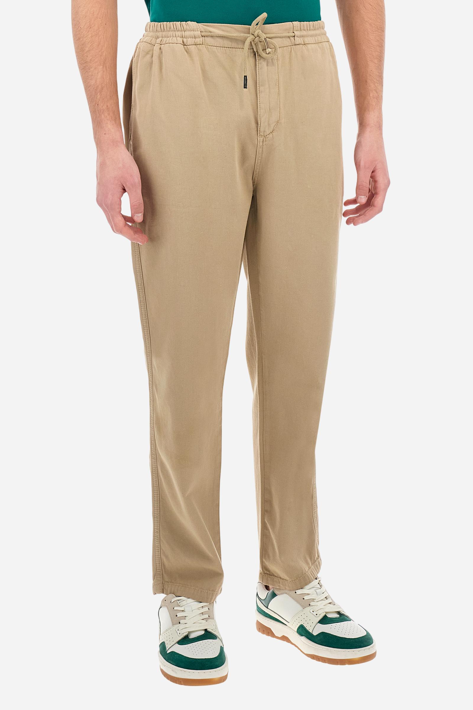 Men's plain straight-cut trousers, made of linen and cotton canvas. Featuring a waist belt at the back and on the sides with elasticated external drawstring for adjustment. The front opening also has a faux horn button on the belt and a zip. Double welt pocket inserted into the sides. There are two additional welt pockets on the back. The logo is featured on the woven label sewn above the right back pocket. Regular fit. The model is wearing a size L. - Twill