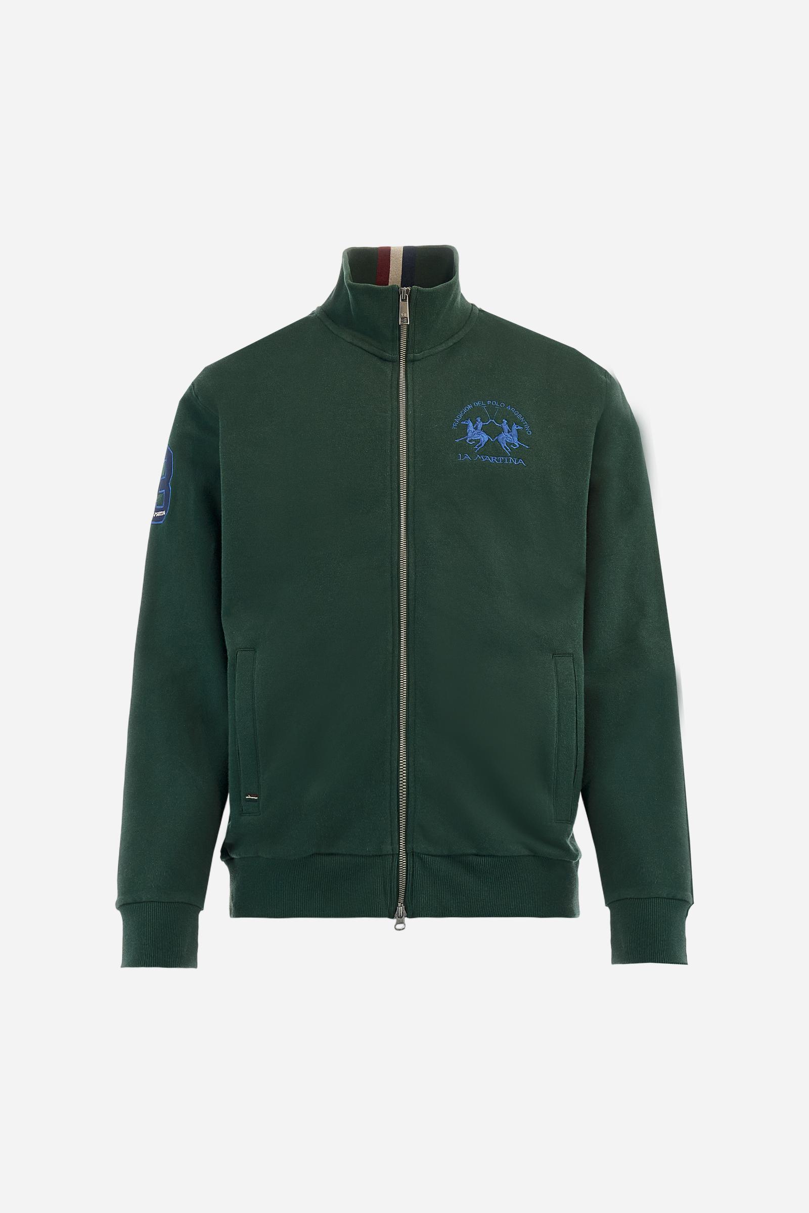 Men's long-sleeved solid colour sweatshirt. It is made of comfortable 100% cotton fleece with a soft-brushed feel. Model with high ribbed neck and front zip opening. Solid colour ribbed cuffs and waistband. The large contrasting brand team logo is embroidered on the chest. A contrasting colour fabric number patch is applied to the right sleeve. The model has a regular fit that offers a comfortable, relaxed silhouette. The model is wearing a size L. - Sycamore