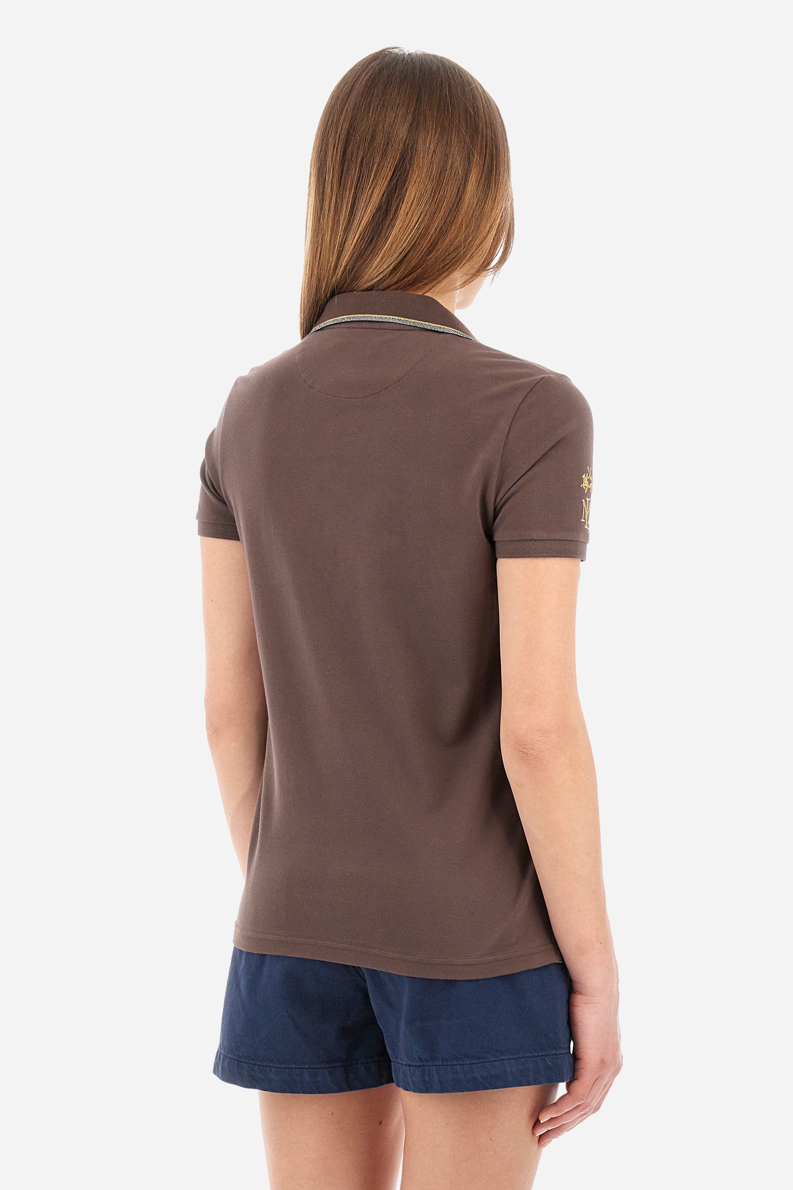 Women’s polo with short sleeves in solid color. Made of stretch cotton. V-neck and jewel button closure. Ribbed crew neck and armhole, both profiled by a lamé strip. The under collar embellished with a different color print along with mini logo and symbol on the chest and sleeve are characteristic of the capsule Guards. The fit is regular. The model wears a size 2. - French Roast