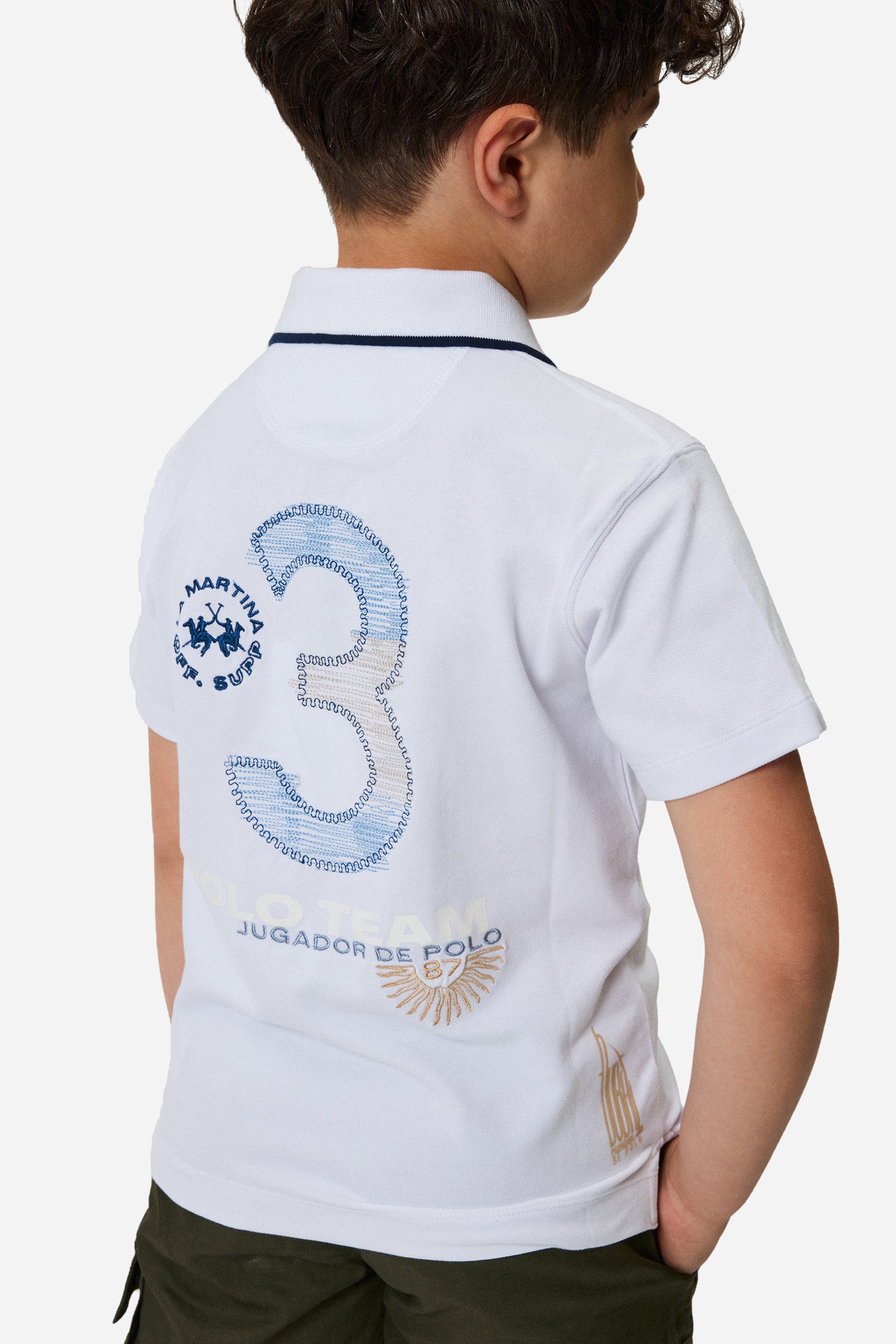 Boys' single-colour polo shirt made of pique cotton. Two-button fastening. Profiled collar with contrasting colour thread. There are various embroideries and rubberised prints on the front of the garment. The logo is on the chest, left side. - Optic White