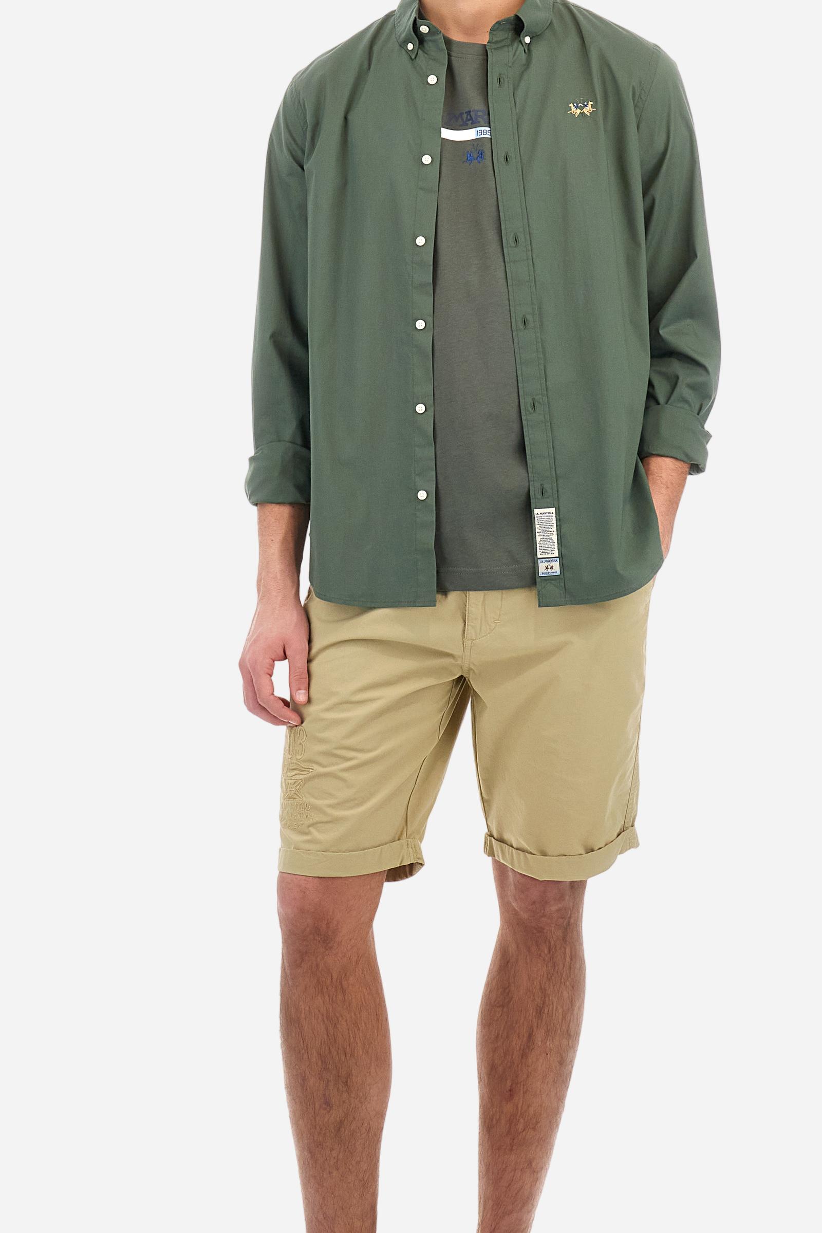 Men's plain long-sleeved shirt made from stretch cotton poplin for a comfortable fit. Featuring a button-down collar and woven labels at the bottom of the opening. A multicoloured logo is embroidered on the chest, over the heart, in contrasting thread. The slim fit ensures a sleek and modern look. The model is wearing a size L. - Thyme