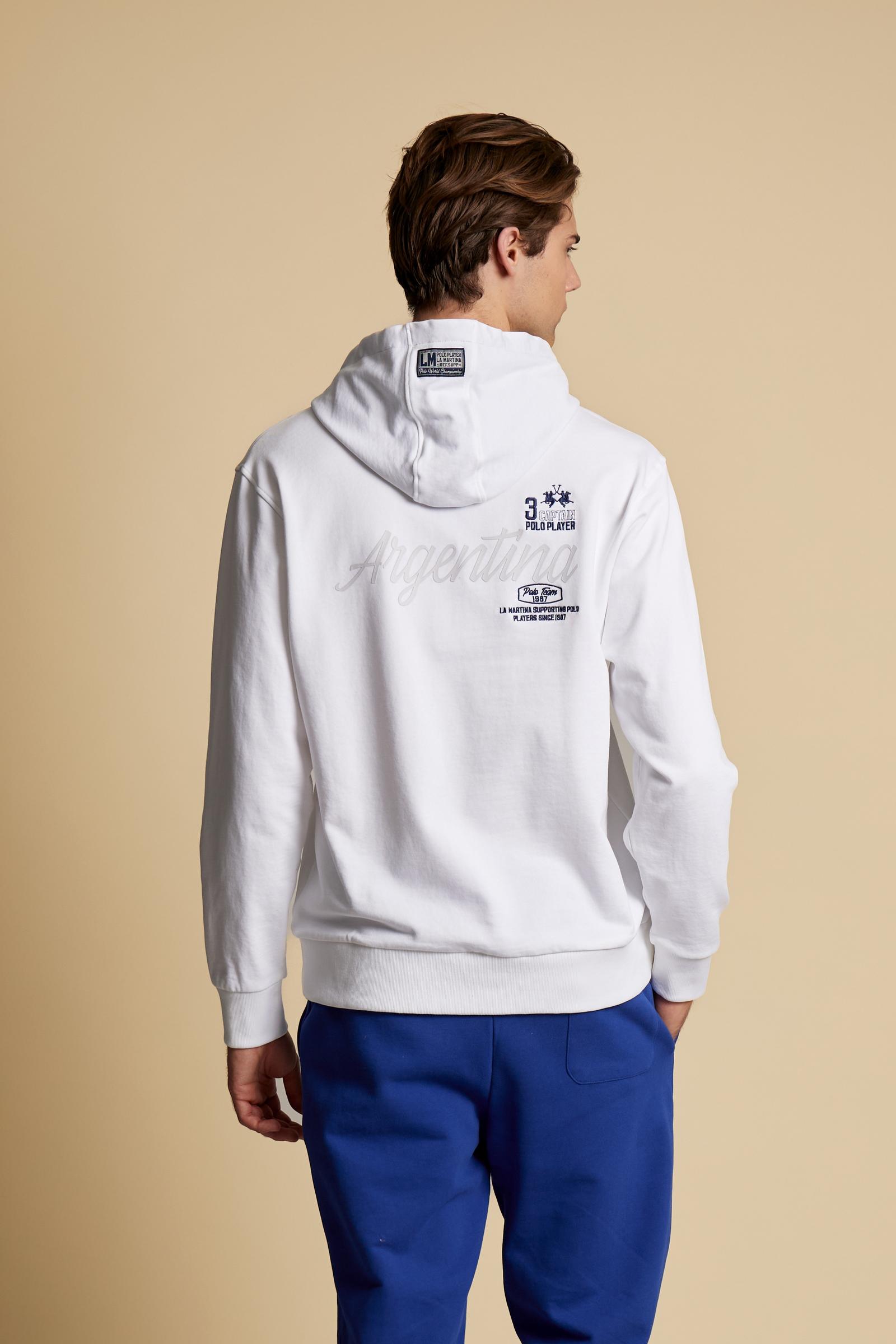 Men’s long-sleeve cotton French terry sweatshirt with a contrast jersey-lined hood, ribbed cuffs, navy embroidery, and a bold Argentina print on the back. - Optic White