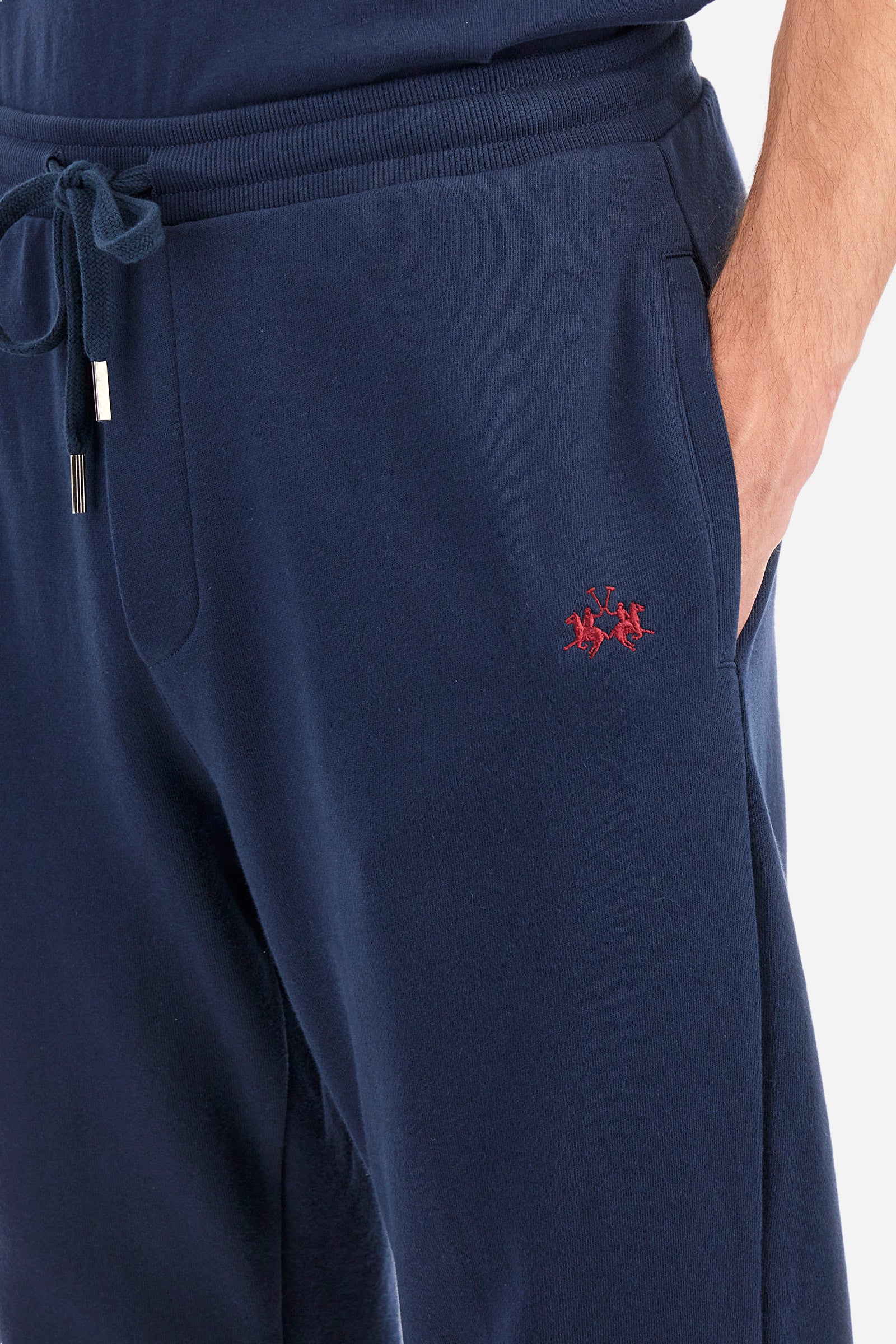 Men's plain jogging bottoms, made from 100% cotton. Drawstring waist and double front pocket. There is an additional pocket on the back. The logo is embroidered on the front. Regular fit. The model is wearing a size L. - Navy