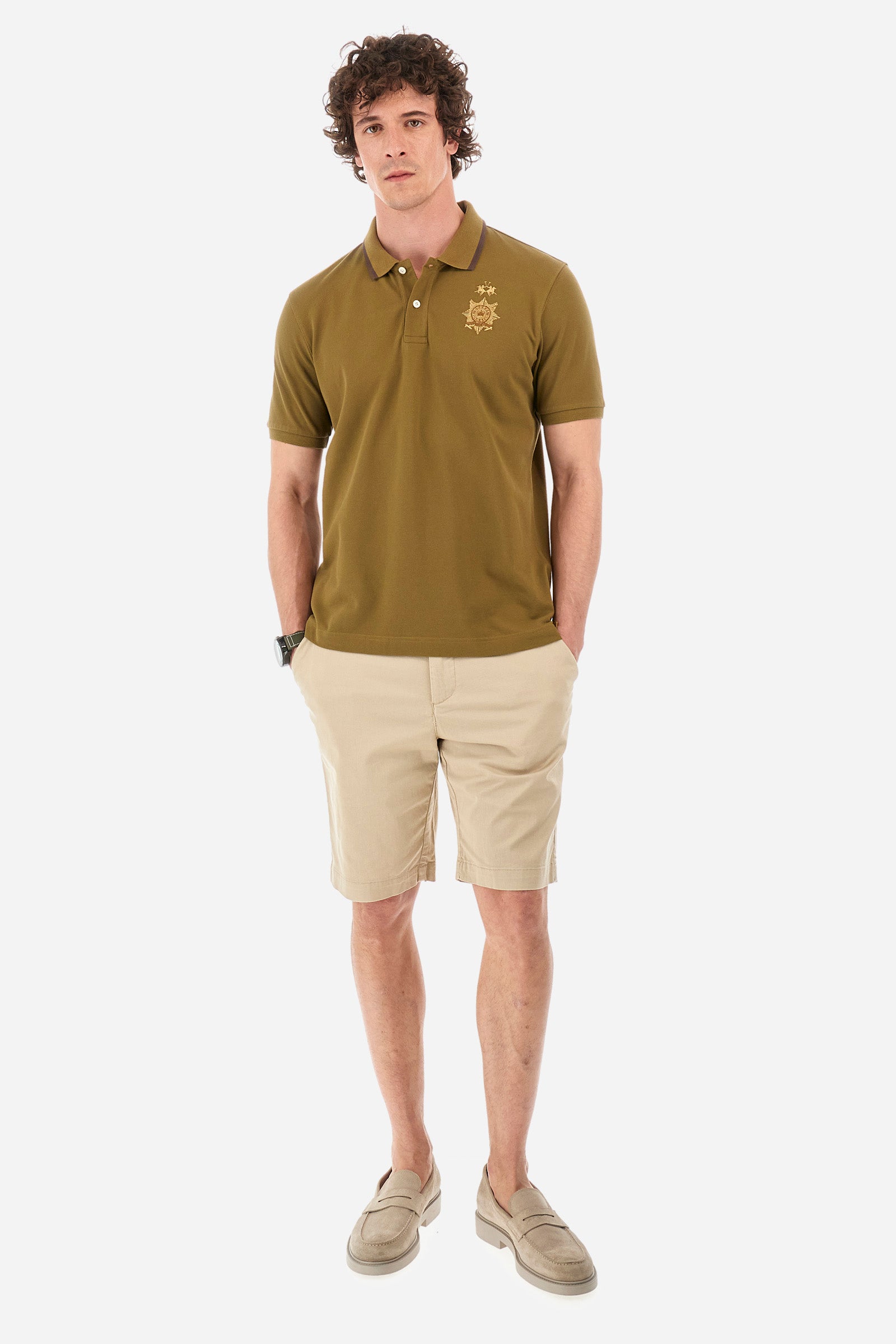 Men's short-sleeved single-colour polo shirt in elasticated cotton. Two-button fastening. Ribbed collar and armholes. The neck is profiled. On the front we find the symbol representing the Guards line. Featuring a small logo embroidered on the chest. The fit is regular. The model wears a size L. - Military Olive