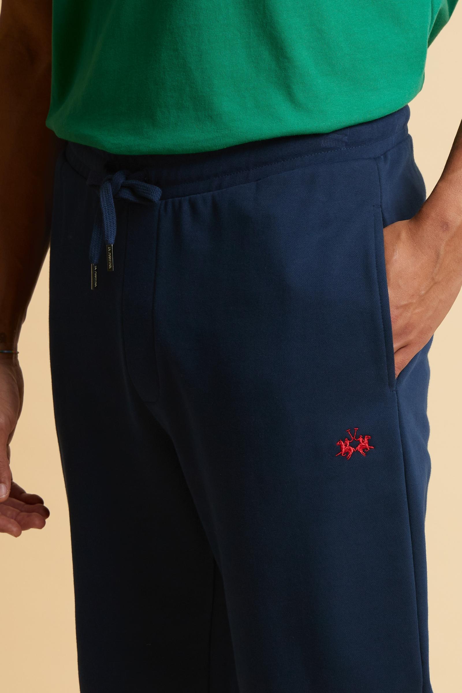 Men’s jogger pants made of soft solid color 100% cotton summer fleece. Minimalist design with tapered cut, comfortable on hips and thighs and slightly narrower toward the hem for a modern, streamlined silhouette. Featuring side slash pockets and adjustable waistband with flat drawstring. Small contrast embroidered brand logo below the left pocket. The model wears size L. - Navy