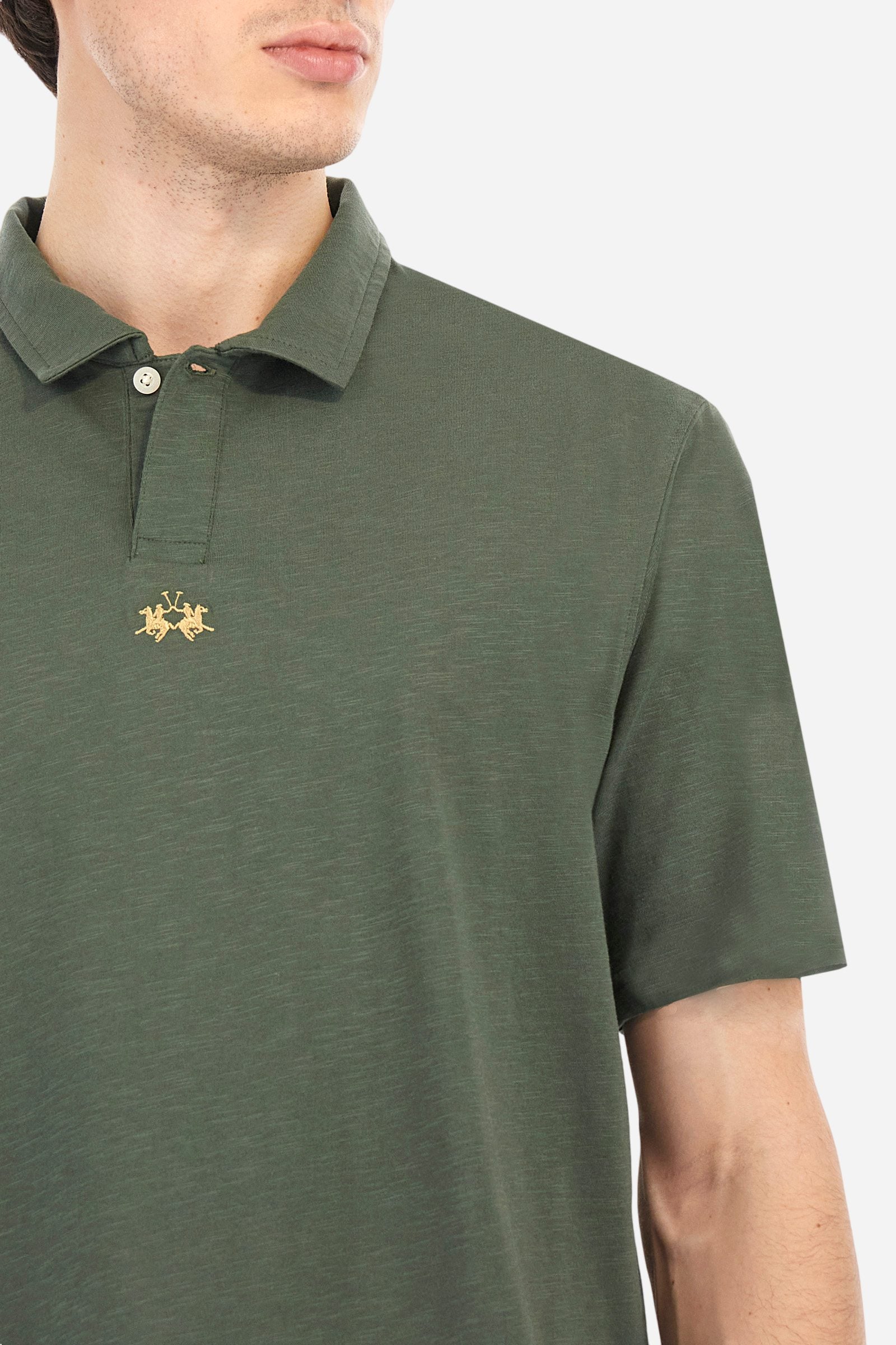 Men's short-sleeved polo shirt in a single colour, made of 100% cotton slub jersey. Fastens with a button. A fabric patch representing the garment's certificate is sewn onto the back. The logo is embroidered in contrast under the opening on the front. Comfort fit. The model is wearing a size L. - Thyme