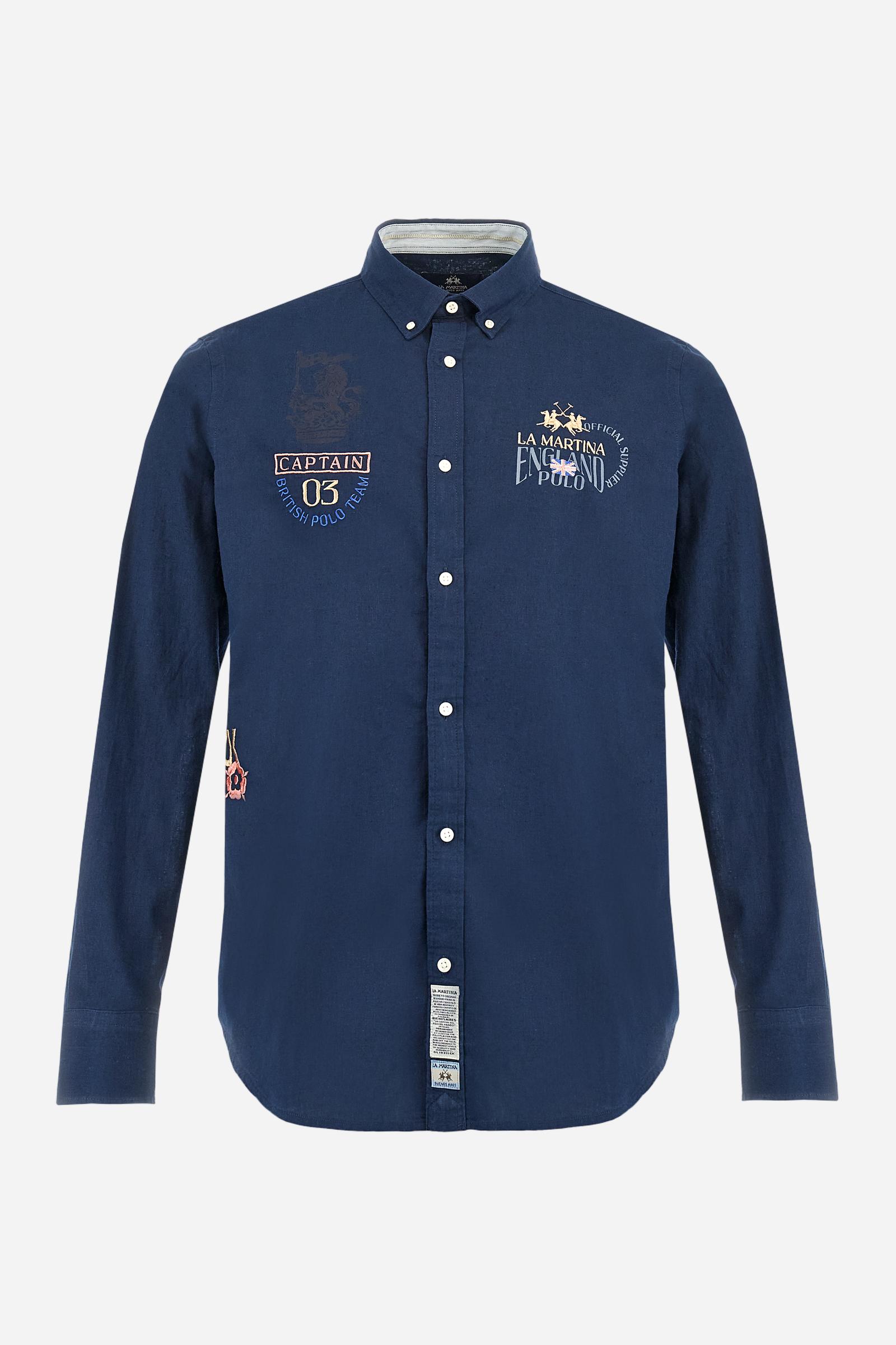 Men's long-sleeved single-colour shirt made of cotton and linen canvas. Button-down collar. Featuring details on the inside of the collar and opening in contrasting colour printed fabrics. The front graphics and logo are embroidered with contrasting colour threads. The fit is regular. The model is wearing a size L. - Navy