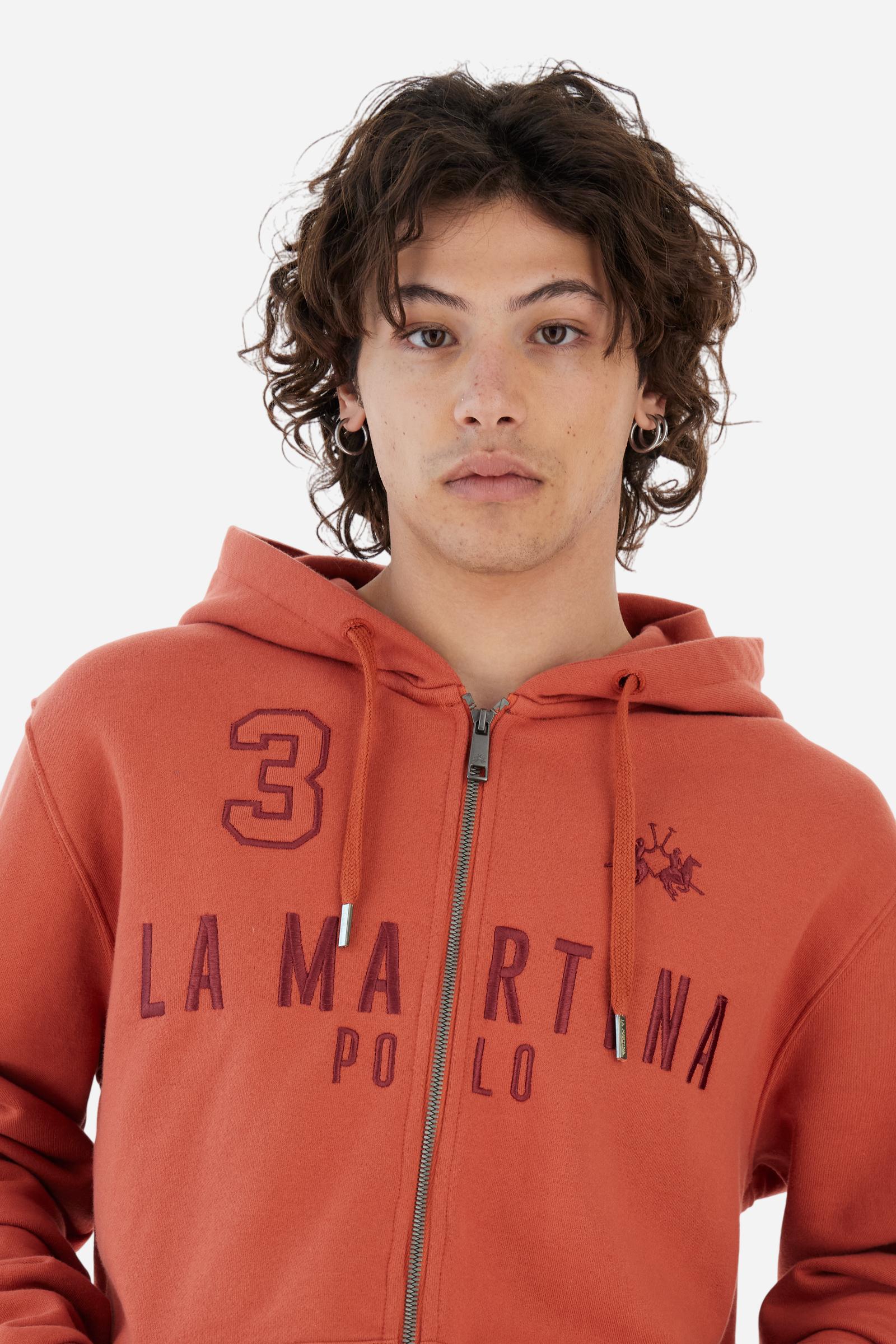 Men's long-sleeved hoodie in solid colour, made from soft 100% cotton fleece with a velvety touch. The model features a customised front zip and an adjustable hood with drawstring. Hem and cuffs in tone-on-tone rib. Iconic brand graphics stand out on the chest, embroidered with numbers and lettering. Regular fit ensuring comfort and freedom of movement. Model wears size L. - Burnt Ochre