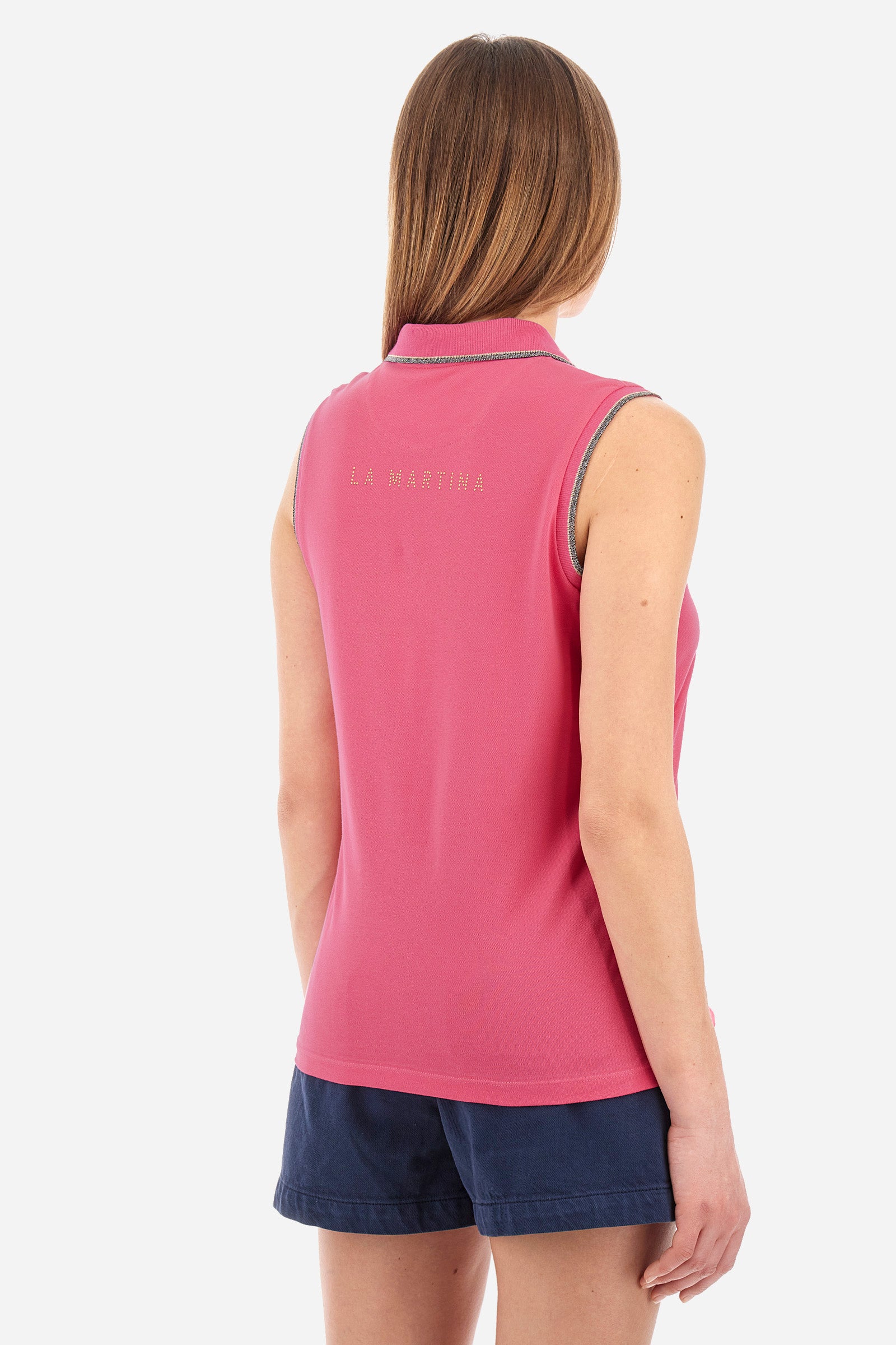 Women’s sleeveless polo shirt in solid color, made of stretch cotton. V-neck and 2 button closure. Collar and crew sleeves profiled and ribbed. Side slits. On the back there is the inscription "La Martina" composed of small rhinestones. The logo is present on the front. The fit is regular. The model wears a size 2 . - Hot Pink
