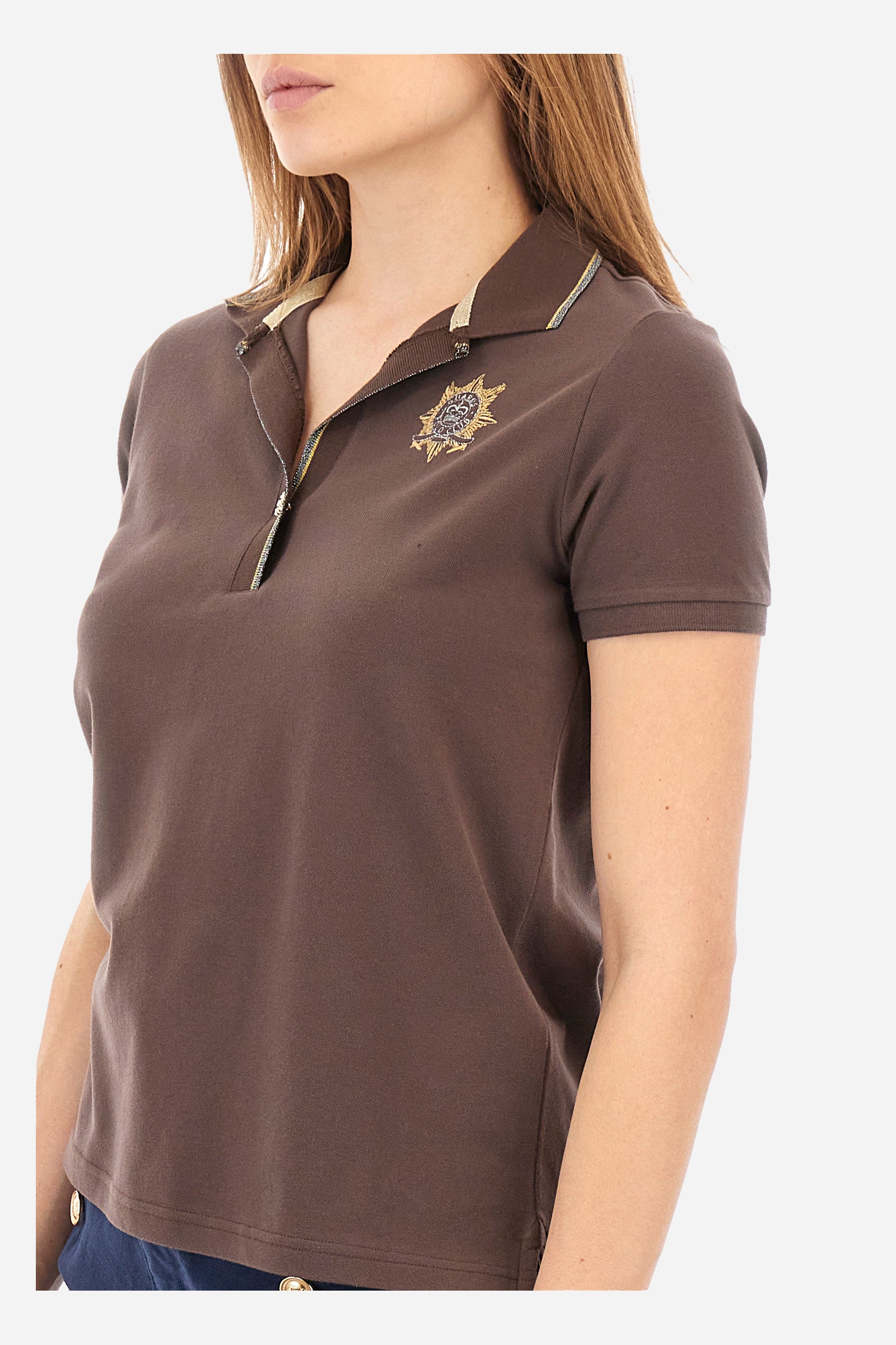 Women’s polo with short sleeves in solid color. Made of stretch cotton. V-neck and jewel button closure. Ribbed crew neck and armhole, both profiled by a lamé strip. The under collar embellished with a different color print along with mini logo and symbol on the chest and sleeve are characteristic of the capsule Guards. The fit is regular. The model wears a size 2. - French Roast