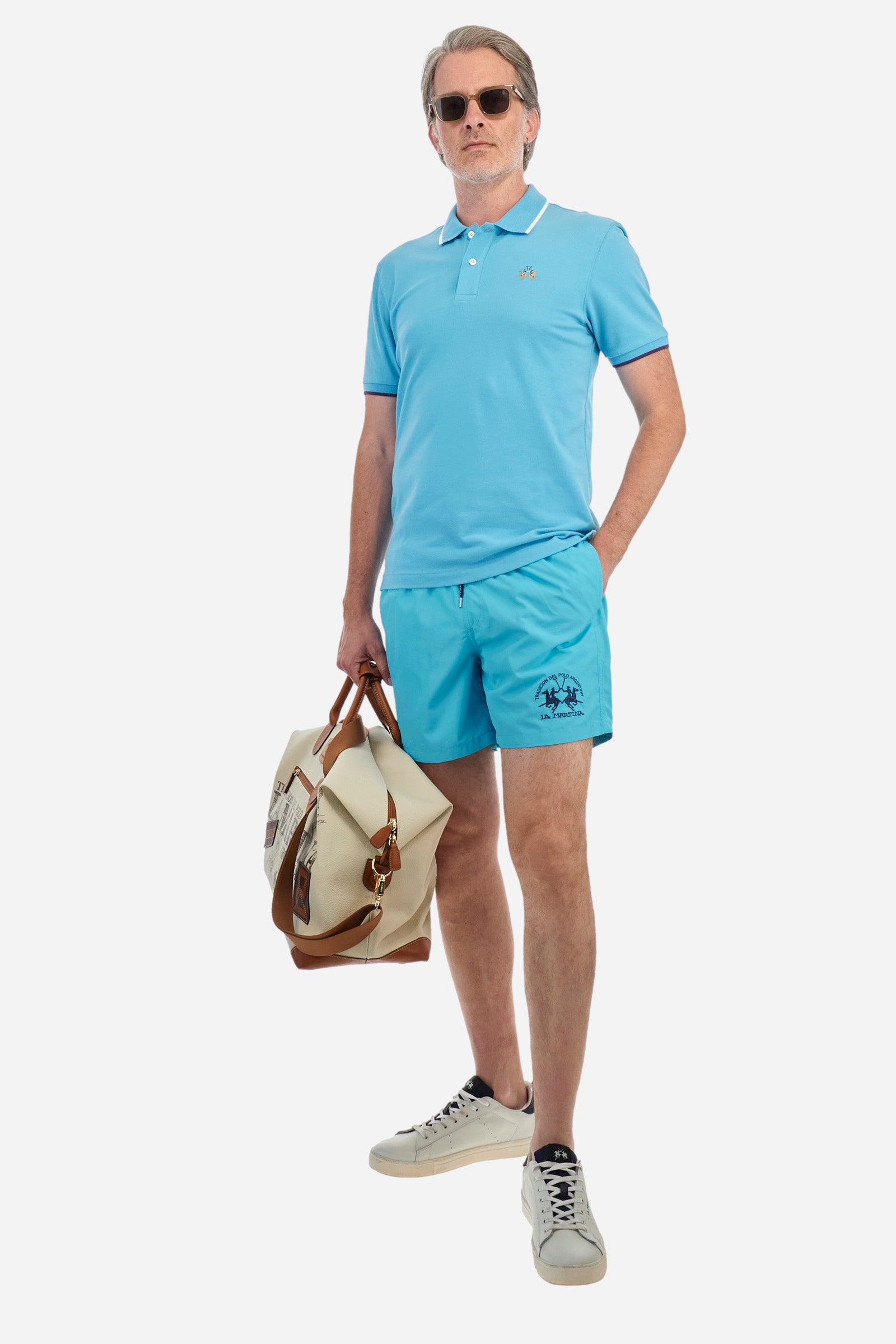 Plain men's swimming shorts made of nylon. Elastic waistband with a personalised drawstring for waist adjustment. On the inside of the shorts is an elasticated mesh brief. Double side pocket on the hips and patch pocket with flap on the back, on the right side only. The large logo is embroidered in a contrasting colour thread on the bottom of the left leg on the front. Regular fit. The model is wearing a size L. - Blue Atoll