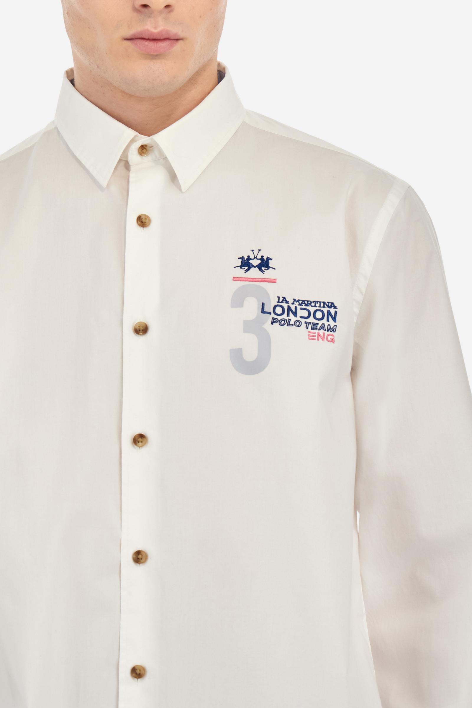 Men's single-colour long-sleeved shirt, made from 100% cotton poplin. Spread collar. Contrasting printed fabric details on the inside of the collar and opening. The numbers on the chest and back graphics are rubberised prints, while the rest of the graphics are embroidered. The logo and La Martina lettering is embroidered on the left chest. The fit is regular. The model is wearing a size L. - Optic White