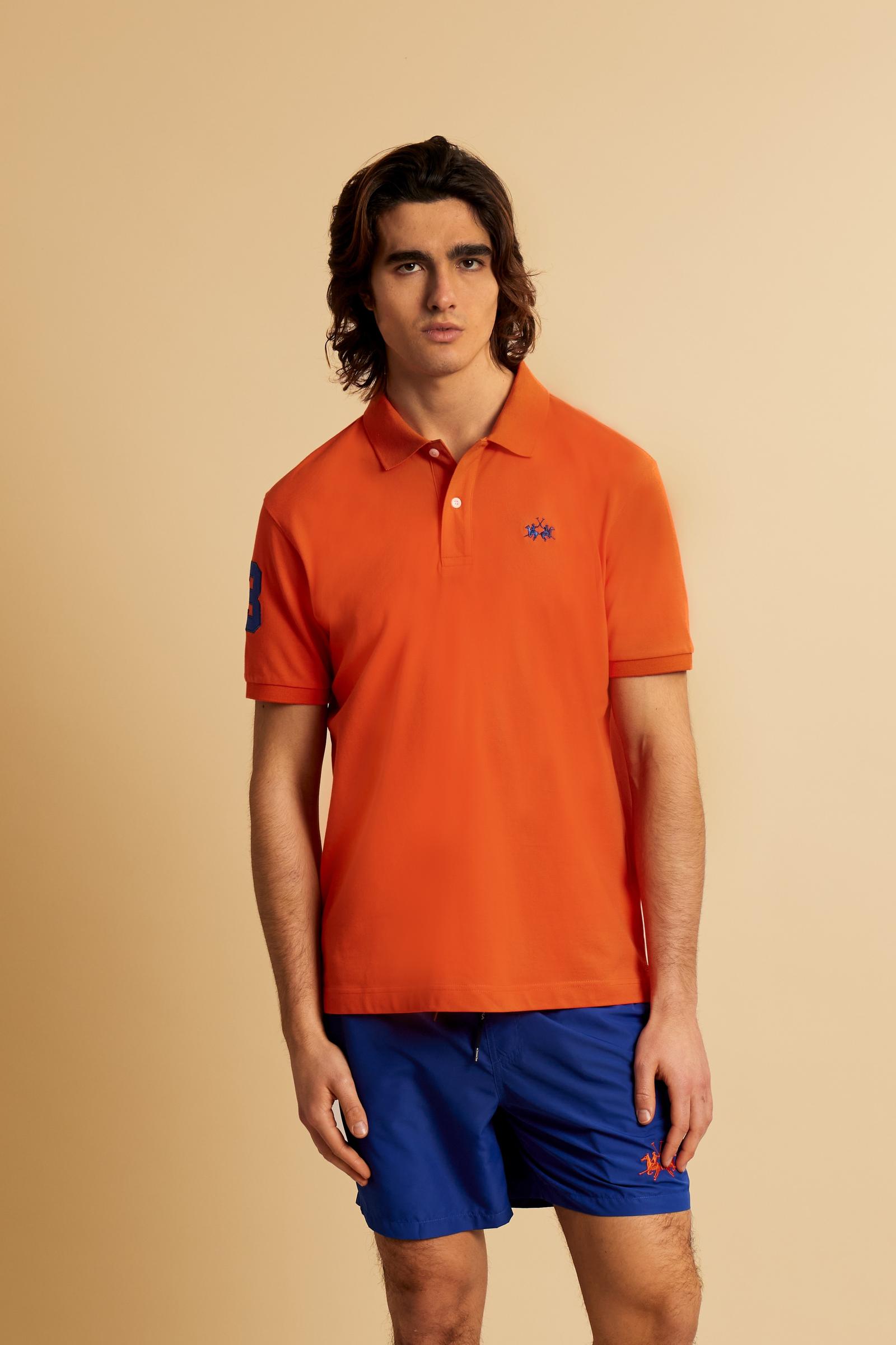 Men’s short-sleeve stretch piqué polo. Two-button placket with ribbed collar and cuffs in solid colour. Numeric patch applied on the sleeve and contrast monogram print under the collar. Small logo embroidered in contrast on the chest. Regular fit. The model wears size L. - Flame