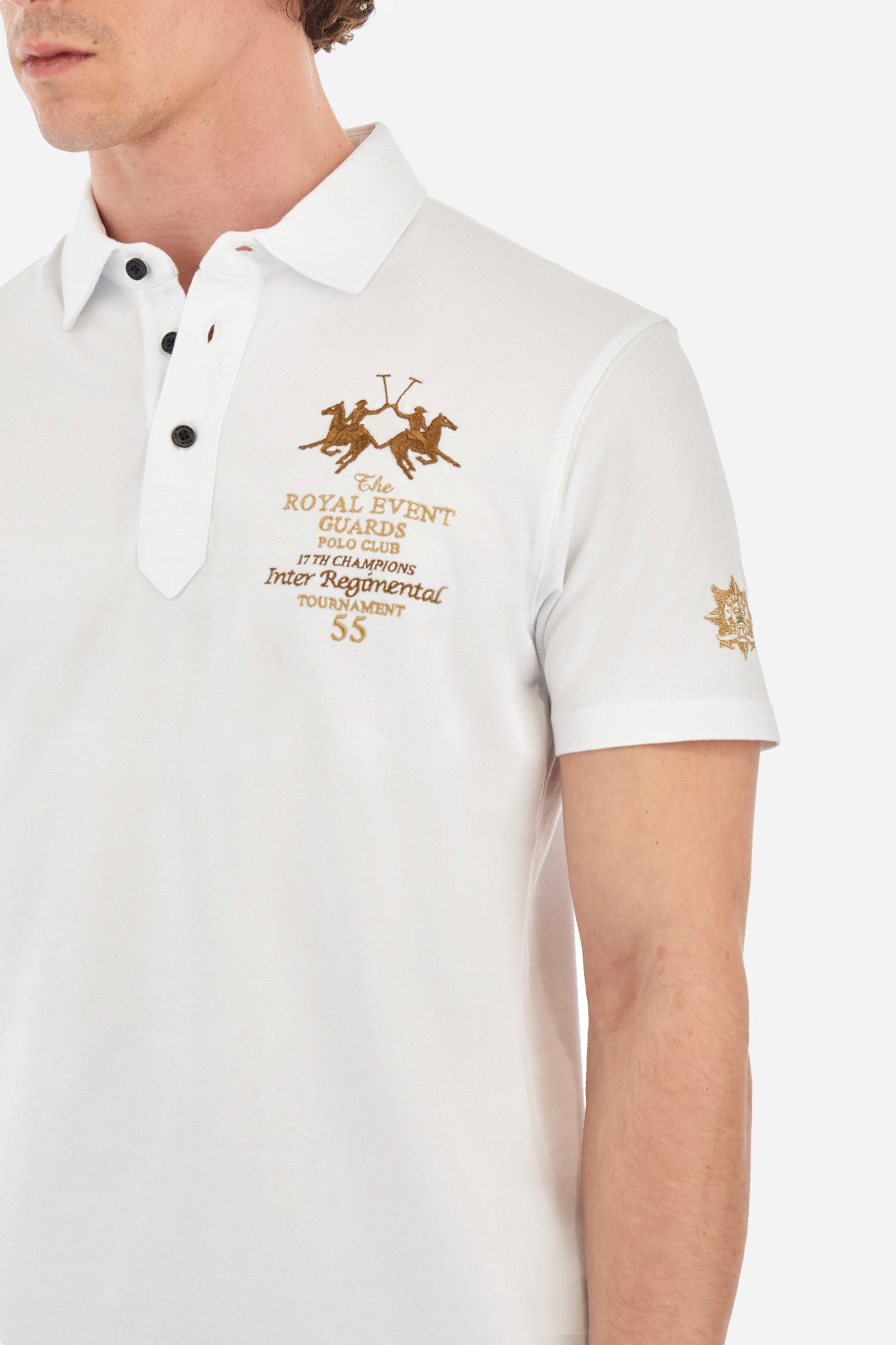Men's short-sleeved single-colour polo shirt in elasticated cotton. Two-button fastening. Pointed collar. On the front we find copper-coloured lettering and a large logo. On one of the sleeves there is a symbol representing the Guards line. The fit is regular. The model wears a size L. - Optic White