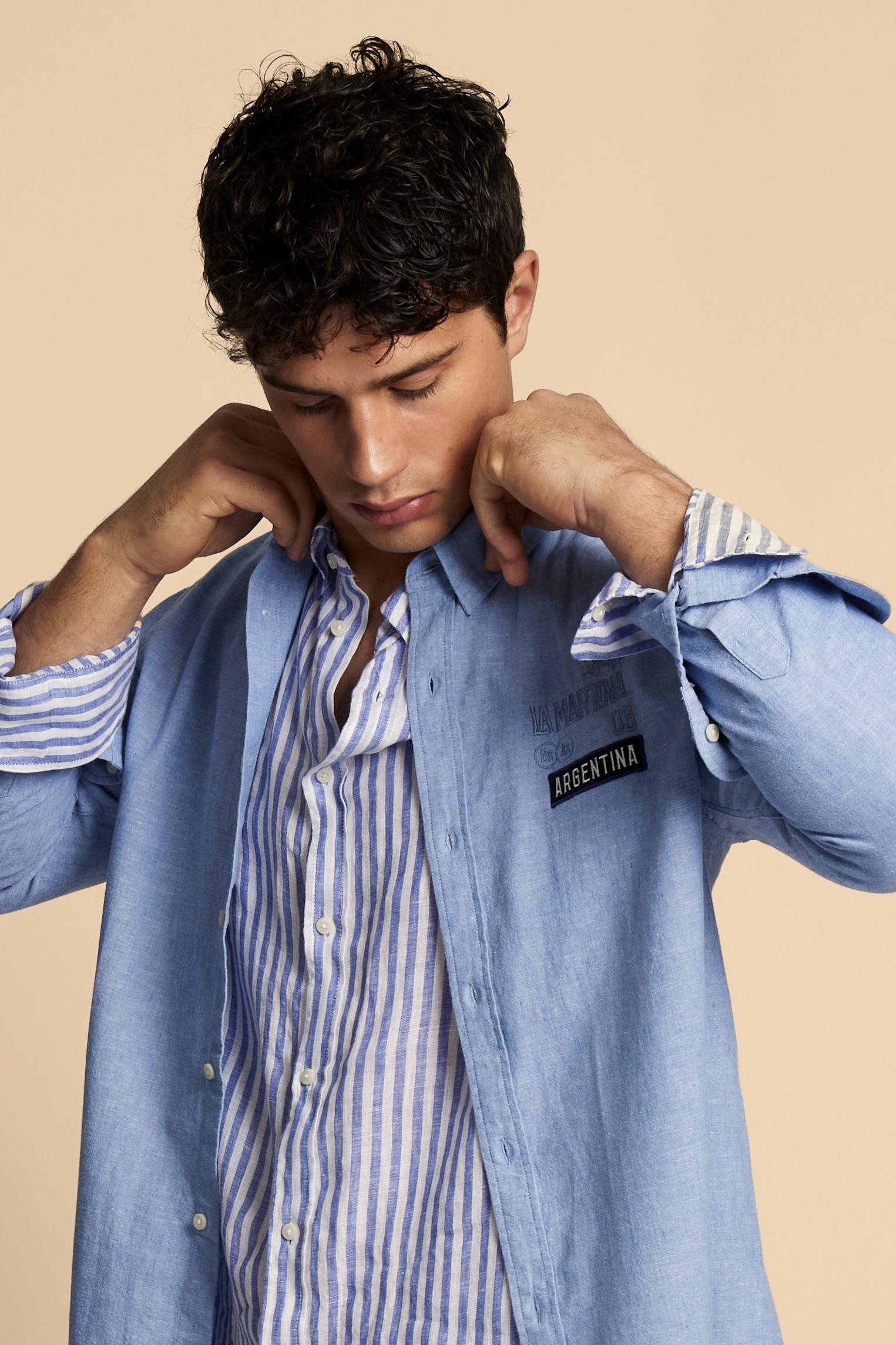 Men’s long-sleeve shirt in premium natural cotton and linen blend, lightweight and breathable with the typical slub texture of linen. The classic cut with regular fit, pointed collar, adjustable cuffs and slightly rounded hem ensures comfort and versatility. Printed and embroidered graphics define the character of the piece: the back features the maxi “Polo Player Argentina” lettering with numeric and technical logo details, while contrasting patches decorate the front. The model wears size L. - Cornflower