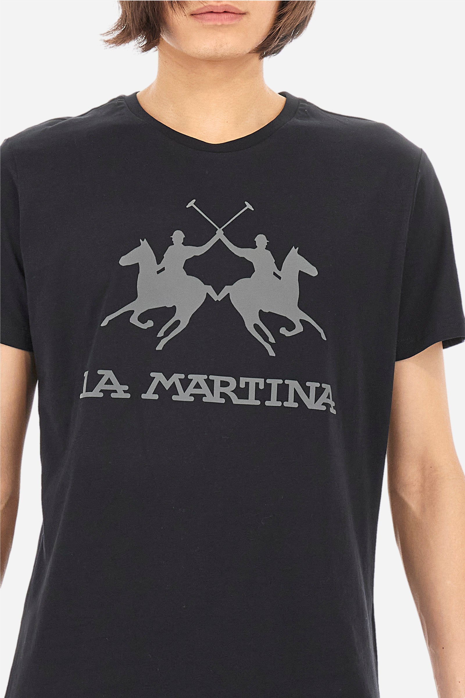 Men's short-sleeved T-shirt with crew neck and solid colour. It features a large printed logo on the front and is made of 100% cotton with a regular fit. It can be combined with trousers for a casual and modern look. The model is 187 cm tall and wears a size L. - Black