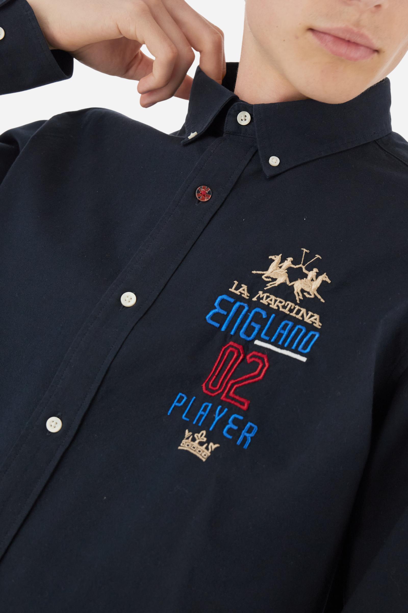 Men's long-sleeved plain shirt made from 100% Oxford cotton. The button-down collar is finished with a second button printed with the English flag. The multicoloured embroidery on the chest, over the heart, includes lettering, numbers and the logo, which add a distinctive touch. Regular fit. The model is wearing a size L. - Navy