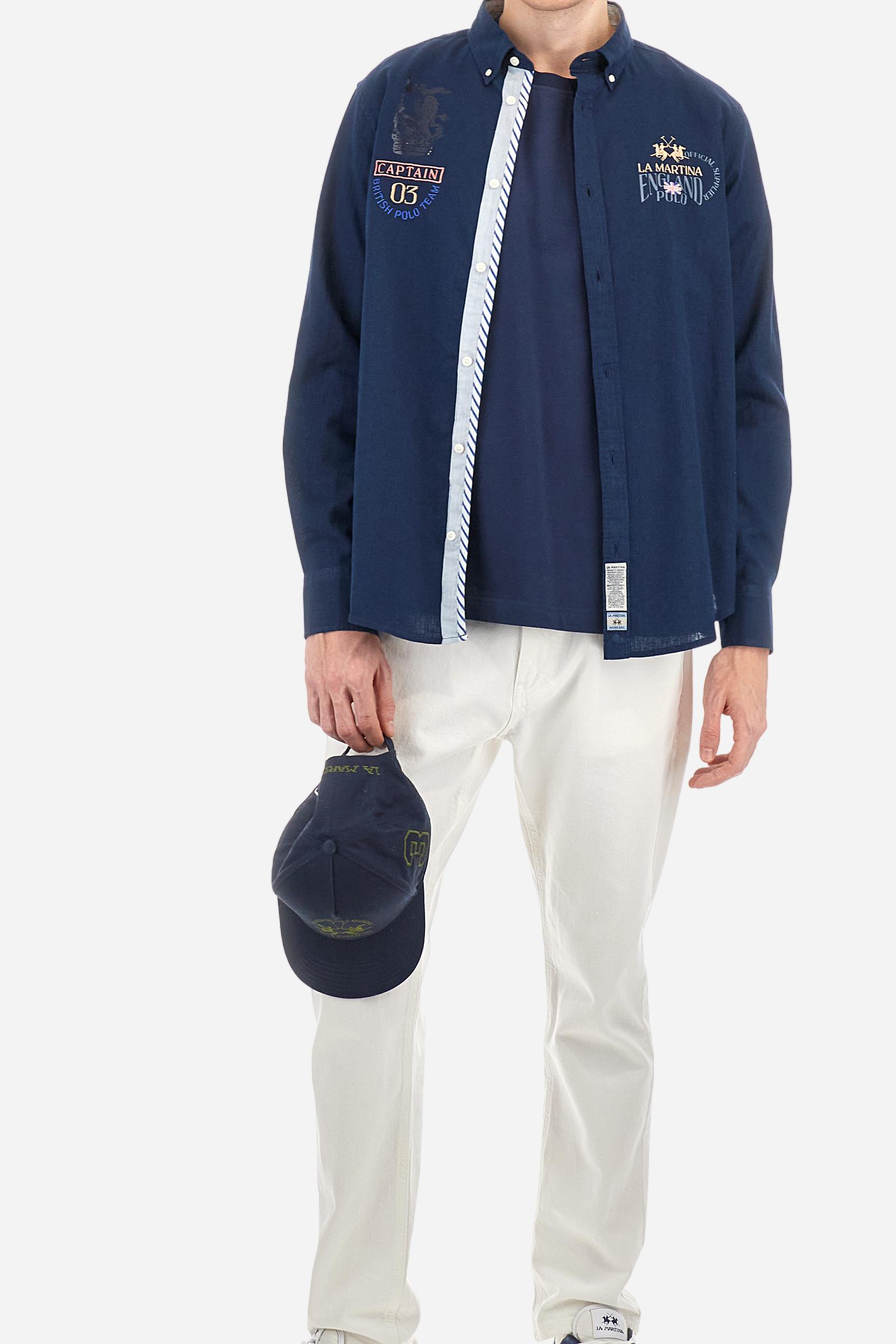Men's long-sleeved single-colour shirt made of cotton and linen canvas. Button-down collar. Featuring details on the inside of the collar and opening in contrasting colour printed fabrics. The front graphics and logo are embroidered with contrasting colour threads. The fit is regular. The model is wearing a size L. - Navy
