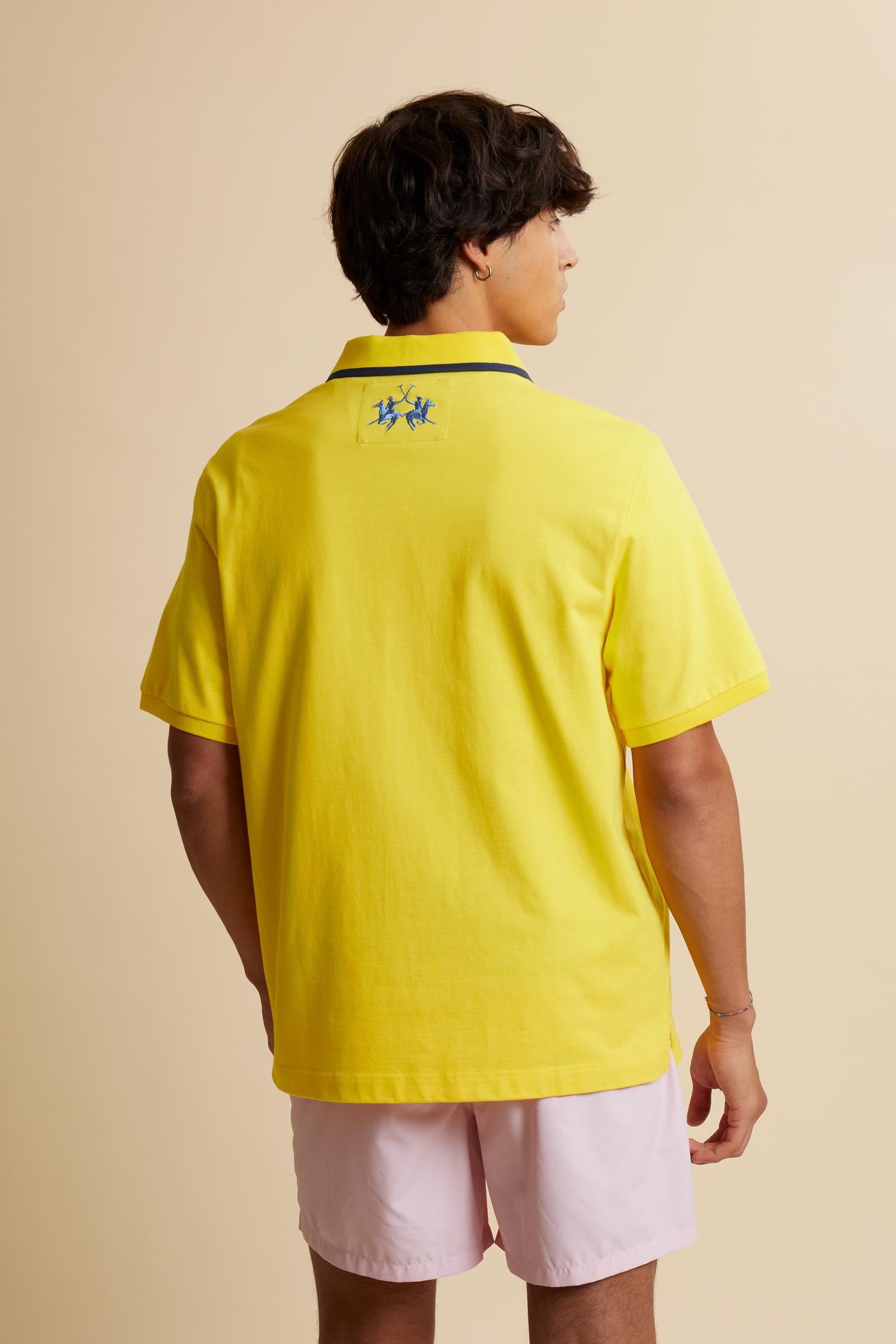 Men's short-sleeve polo shirt made from heavy-weight cotton jersey in solid color. The model features a front opening in contrasting jersey with vertically embroidered chain stitching. The collar and cuffs are ribbed with contrasting edge detail. The design is enriched with an embroidered crest on the chest dedicated to Saint Tropez and the iconic two polo players logo embroidered on the back. The fit follows modern trends with a slightly oversized silhouette, dropped shoulders and a relaxed shape. The mode