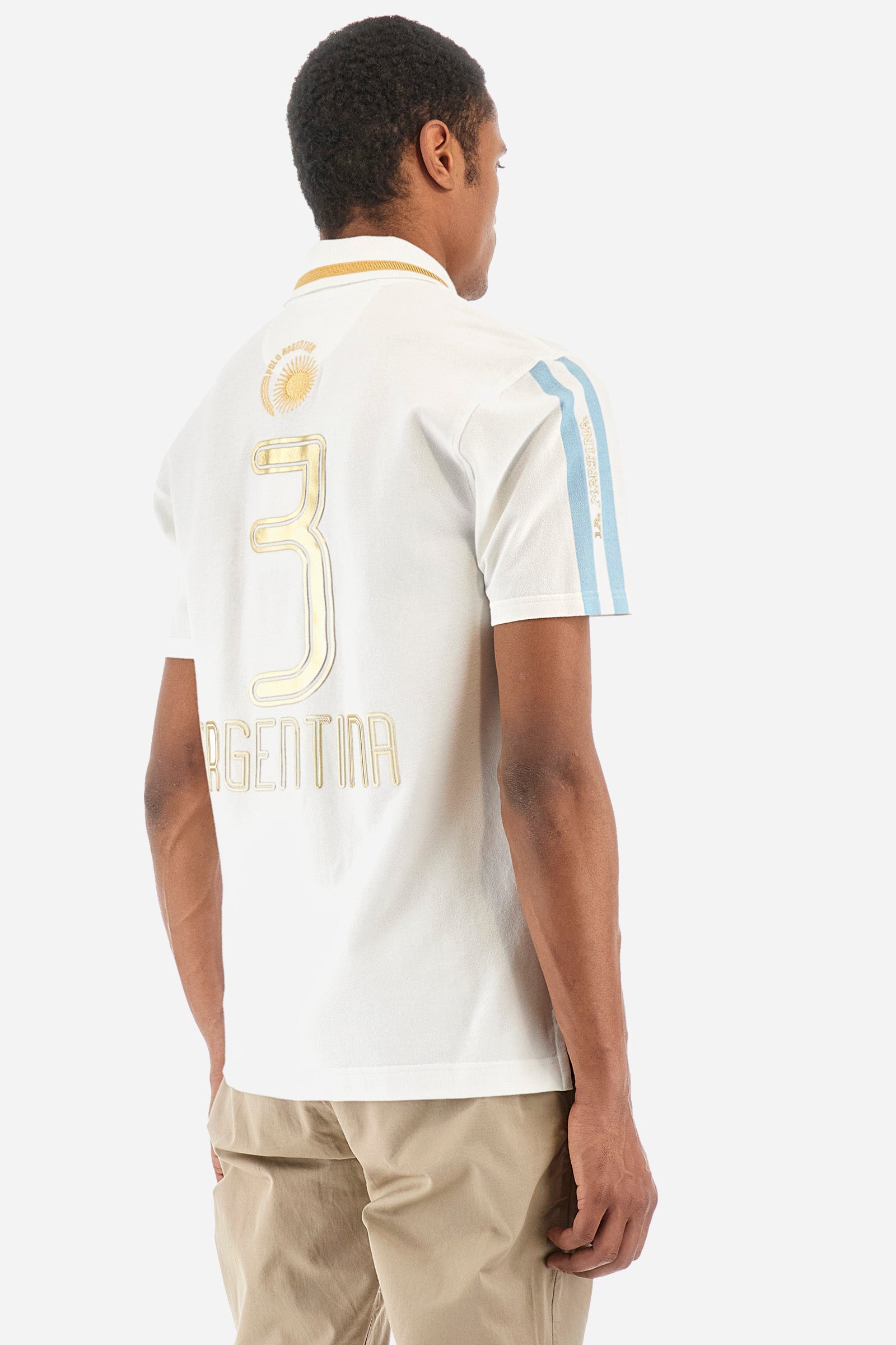 Men's single-colour short-sleeved polo in elasticated cotton. Three-button fastening. Collar with contrasting colour stripe. The front features embroidered lettering, the number 3, the word "Argentina", and a small logo. On one sleeve we find the "La Martina" lettering with two stripes in the colours of the Argentinian flag. The back features additional "Argentina" lettering, a print of the number 3, and symbols representing the nation. The fit is regular. The model wears a size L. - Optic White