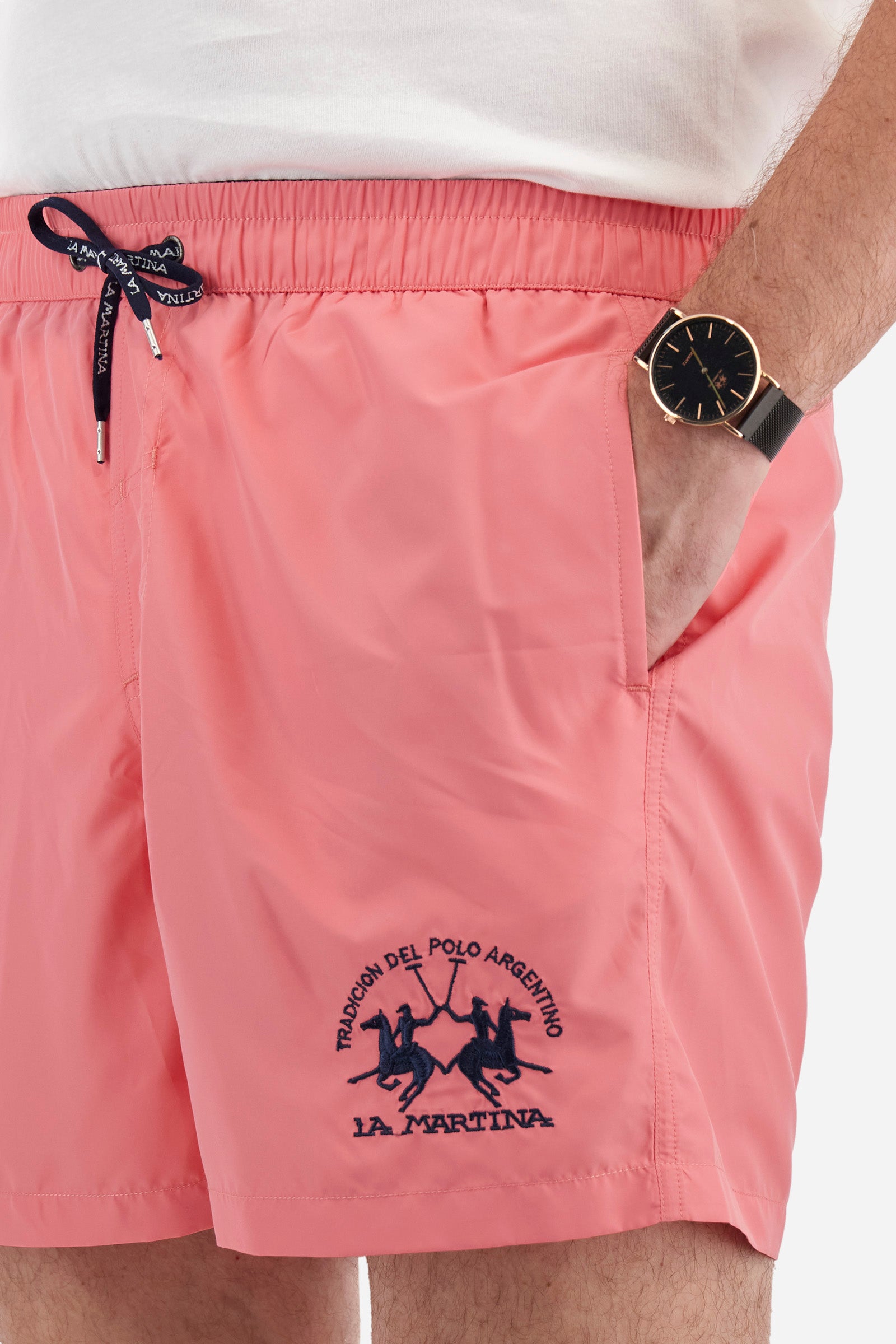 Plain men's swimming shorts made of nylon. Elastic waistband with a personalised drawstring for waist adjustment. On the inside of the shorts is an elasticated mesh brief. Double side pocket on the hips and patch pocket with flap on the back, on the right side only. The large logo is embroidered in a contrasting colour thread on the bottom of the left leg on the front. Regular fit. The model is wearing a size L. - Pink Lemonade