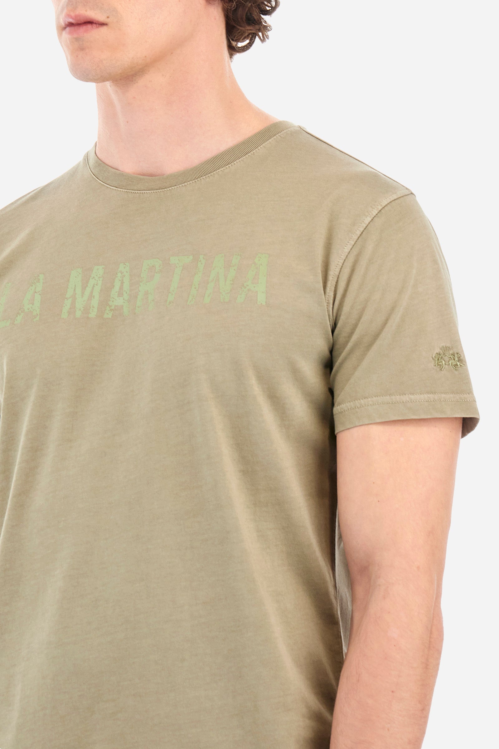 Men's short-sleeved T-shirt with a crew neck in a single colour. Made of 100% cotton. On the front we find the writing "La Martina". A small logo is embroidered tone-on-tone on one of the sleeves. Regular fit. The model wears a size L. - Vetiver