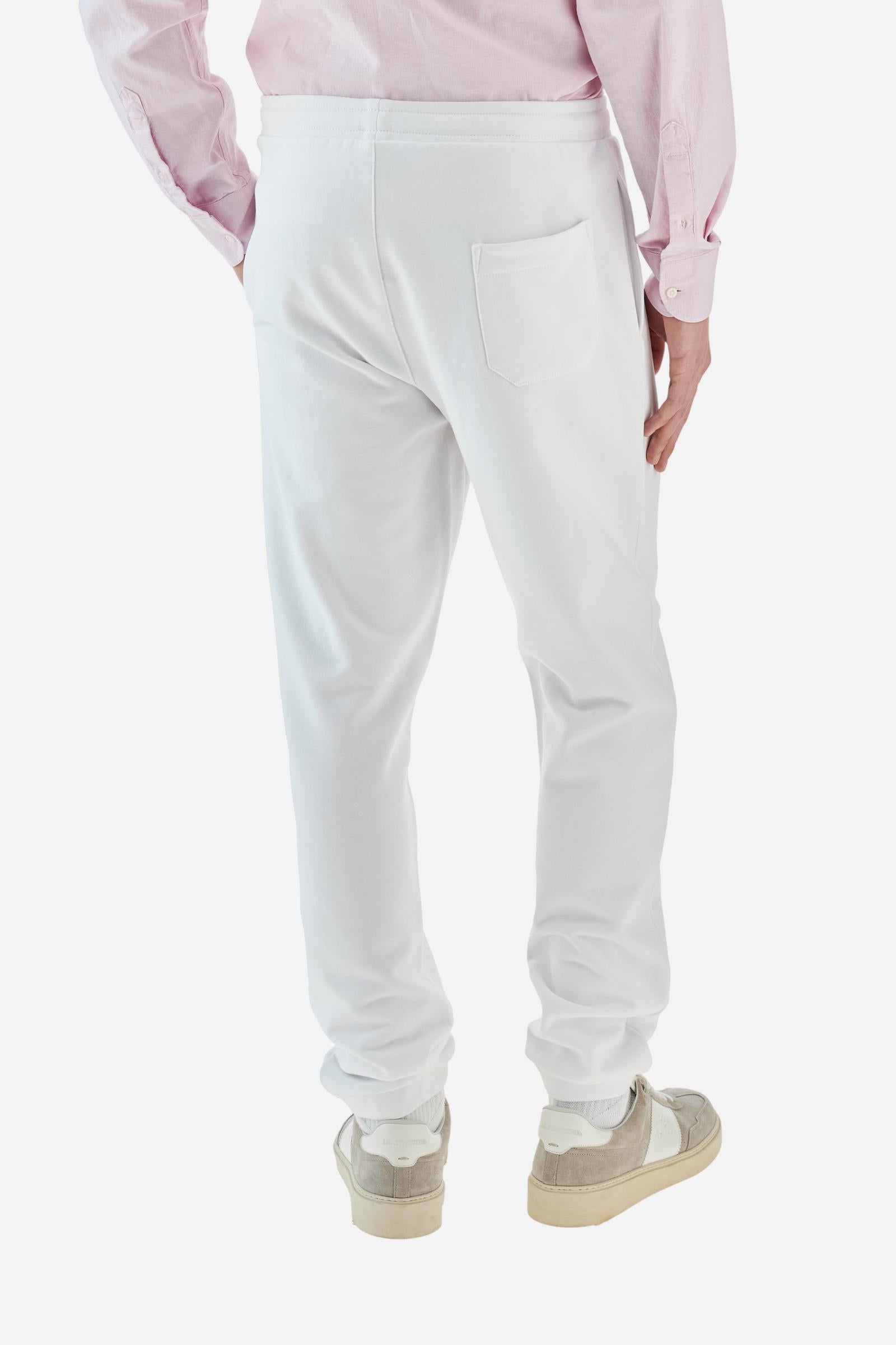 Single-colour men's jogging trousers in a French terry cotton sweat fabric. Removable and adjustable waistband with drawstring. American pockets at the sides. An additional patch pocket is applied on the back. The logo is embroidered in a colour-contrasting thread on the front, left side. The fit is regular. The model is wearing a size L. - Optic White