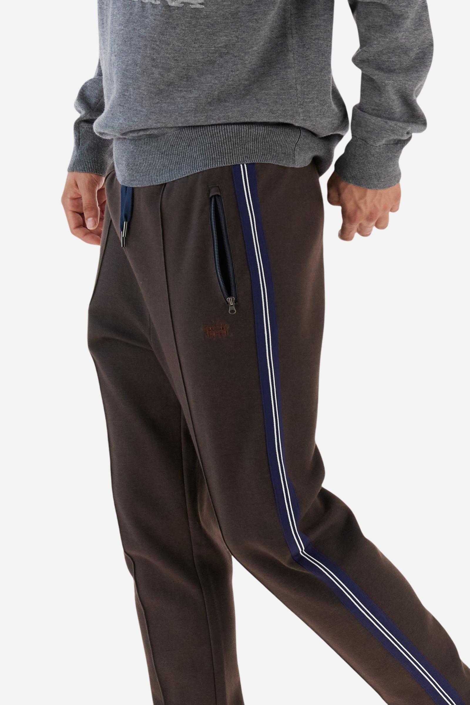 Men’s joggers made of 100% cotton interlock fleece with a bicolor design. Elastic waistband with drawstring for a customizable fit. Two zipped side pockets add practicality, while multicolor striped tape decorates both sides. A vertical crease on the front leg adds refinement to this sporty style. Small embroidered logo in contrast under the left pocket. Regular straight-leg fit for a classic, comfortable silhouette. Model wears size L. - Java