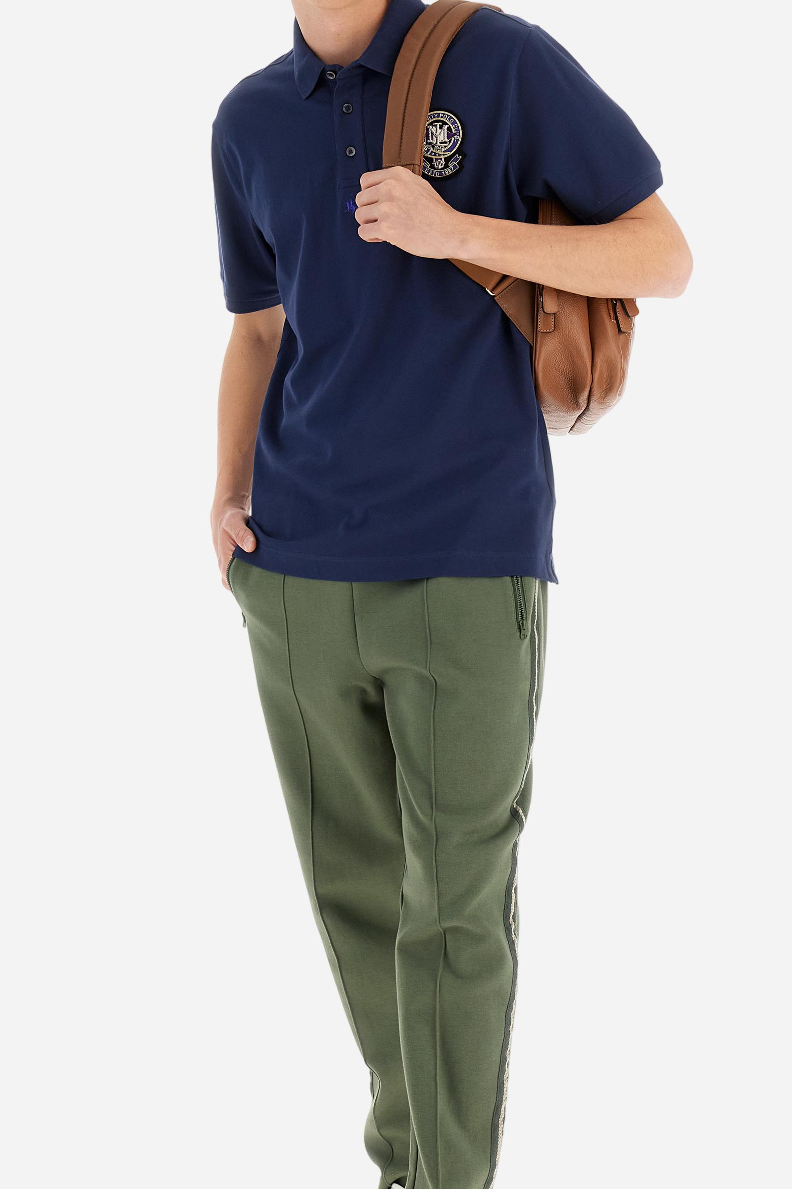 Men's short-sleeved polo shirt in a single colour, made of cotton stretch pique. Fastens with three buttons. Cuffs and collar in rib knit to match the garment. Patch in metallic thread applied on the chest. A colour-contrasting logo is present on the front. Regular fit. The model is wearing a size L. - Navy