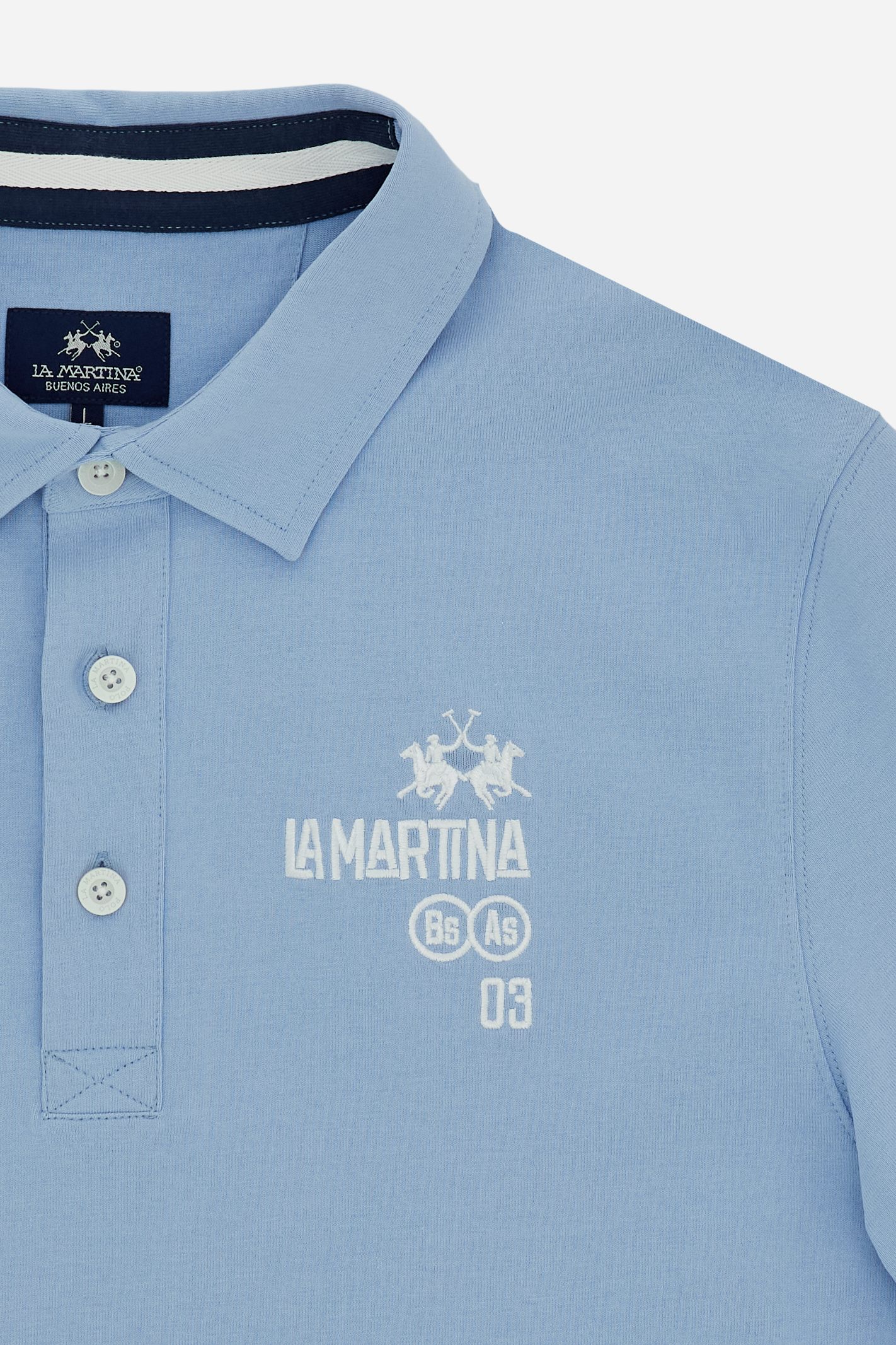 Men’s heavy cotton jersey polo with three-button placket and striped details. Celebratory maxi graphic and bold lettering. - Blue Bell