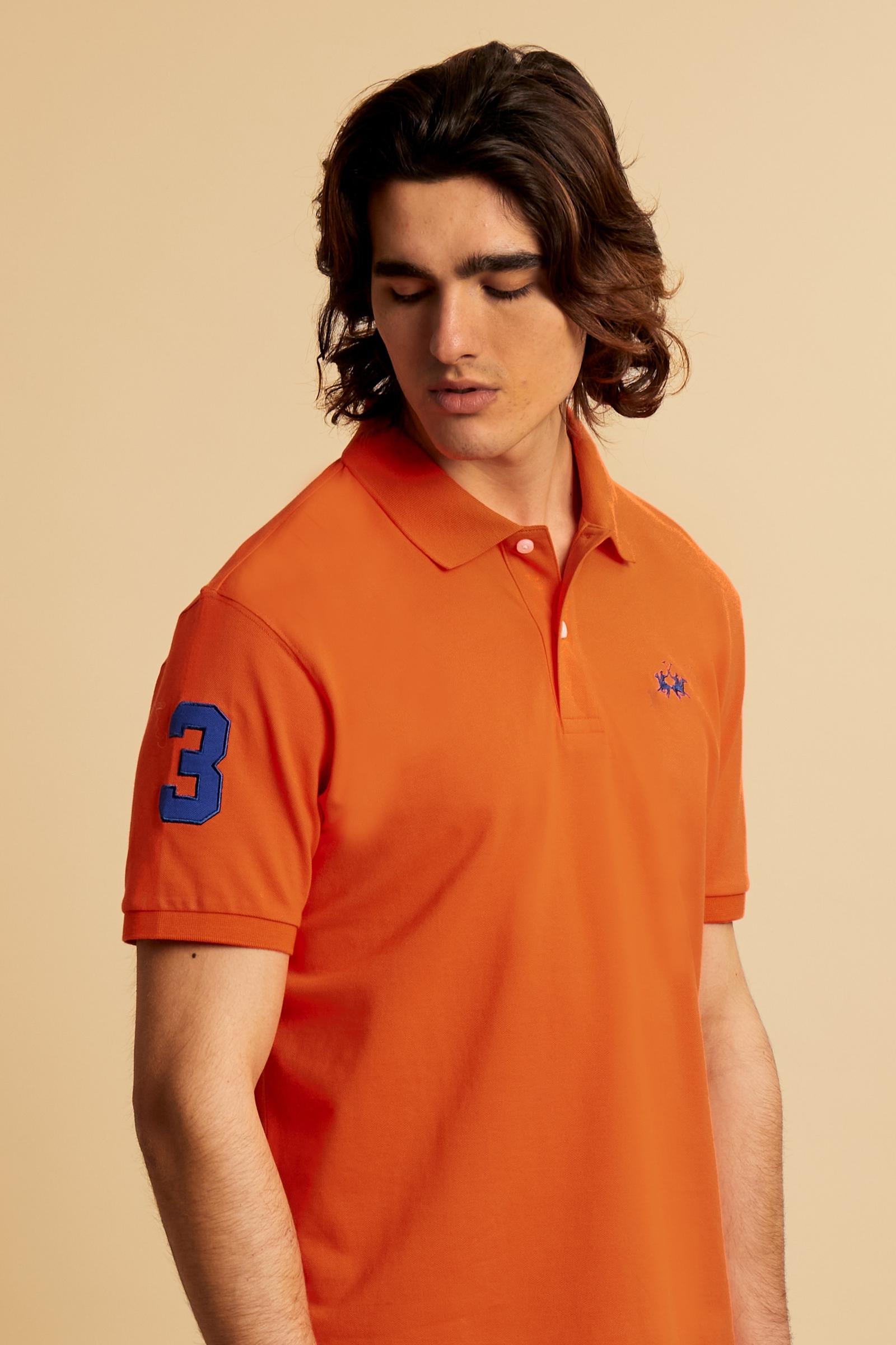 Men’s short-sleeve stretch piqué polo. Two-button placket with ribbed collar and cuffs in solid colour. Numeric patch applied on the sleeve and contrast monogram print under the collar. Small logo embroidered in contrast on the chest. Regular fit. The model wears size L. - Flame