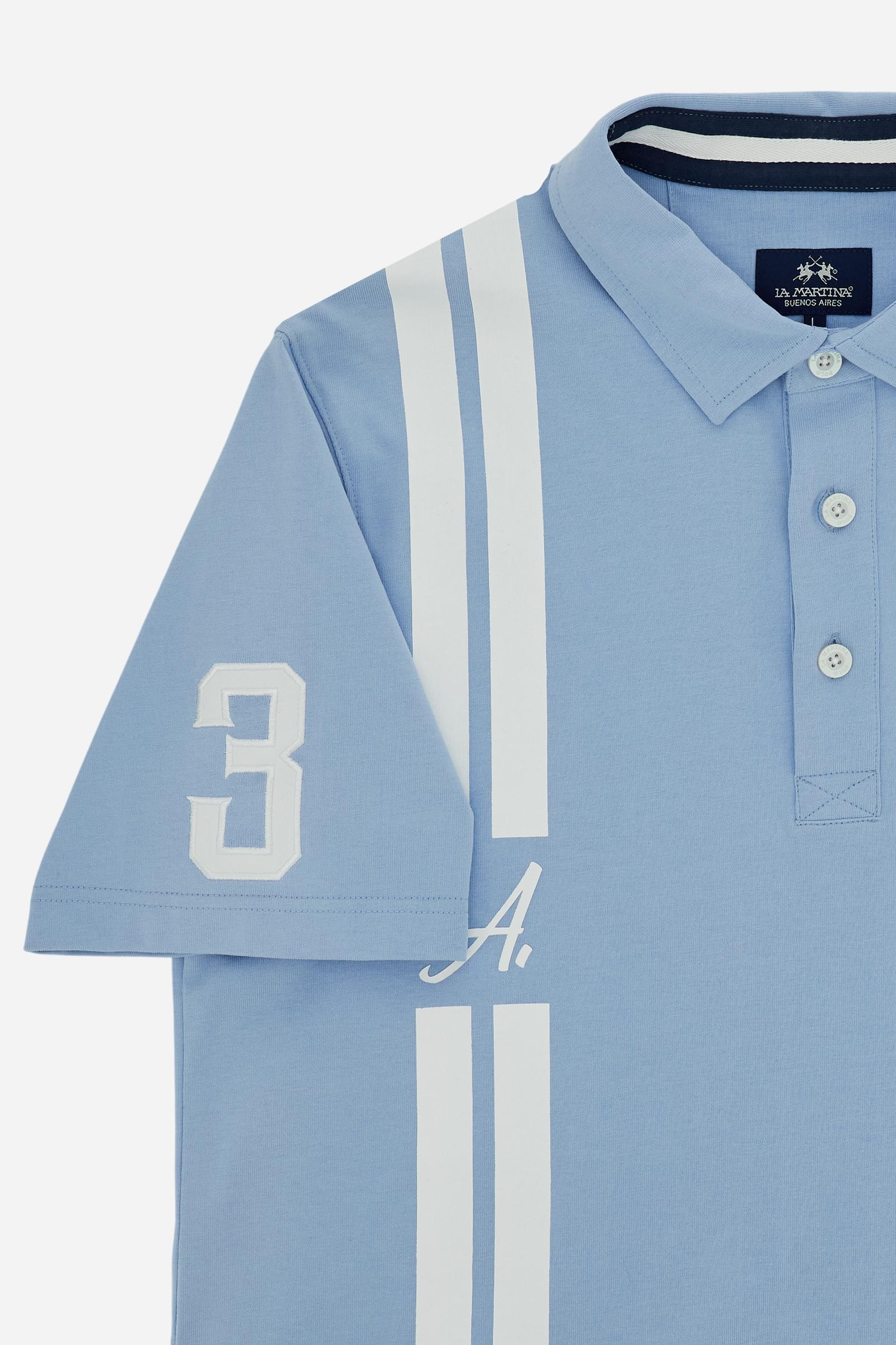 Men’s polo in 100% high-weight cotton jersey with a contemporary silhouette. Three-button placket and ribbed collar. Contrast vertical stripe detail and minimal chest prints enhance the dynamic design. The back features a bold maxi “A” graphic with celebratory lettering and a number 3 patch on the right sleeve. The model wears size L. - Blue Bell