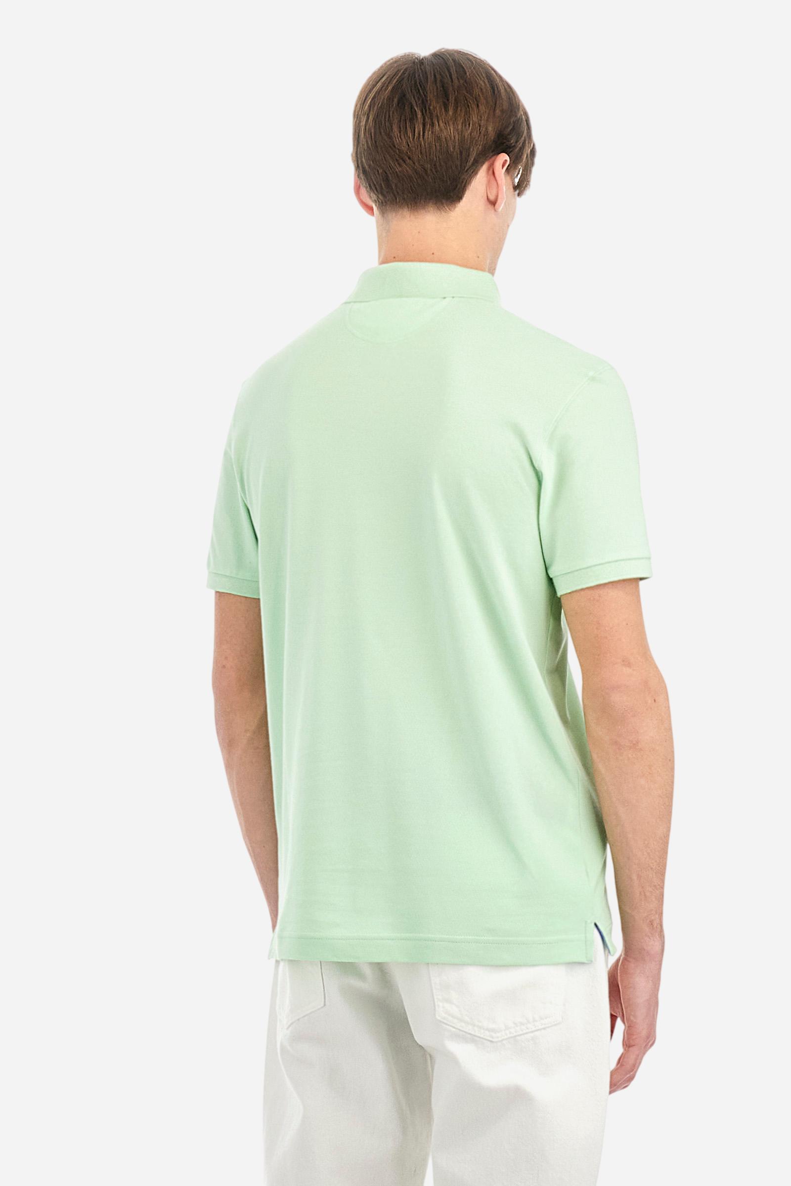 Men's plain short-sleeved polo shirt made from stretch piqué. Two-button fastening. The collar and cuffs are made from tone-on-tone ribbed fabric. Under the collar, there is a contrasting fabric panel with embroidered multicoloured lettering. The logo is embroidered on the left side of the chest in contrasting thread. Slim fit. The model is wearing a size L. - Pastel Green