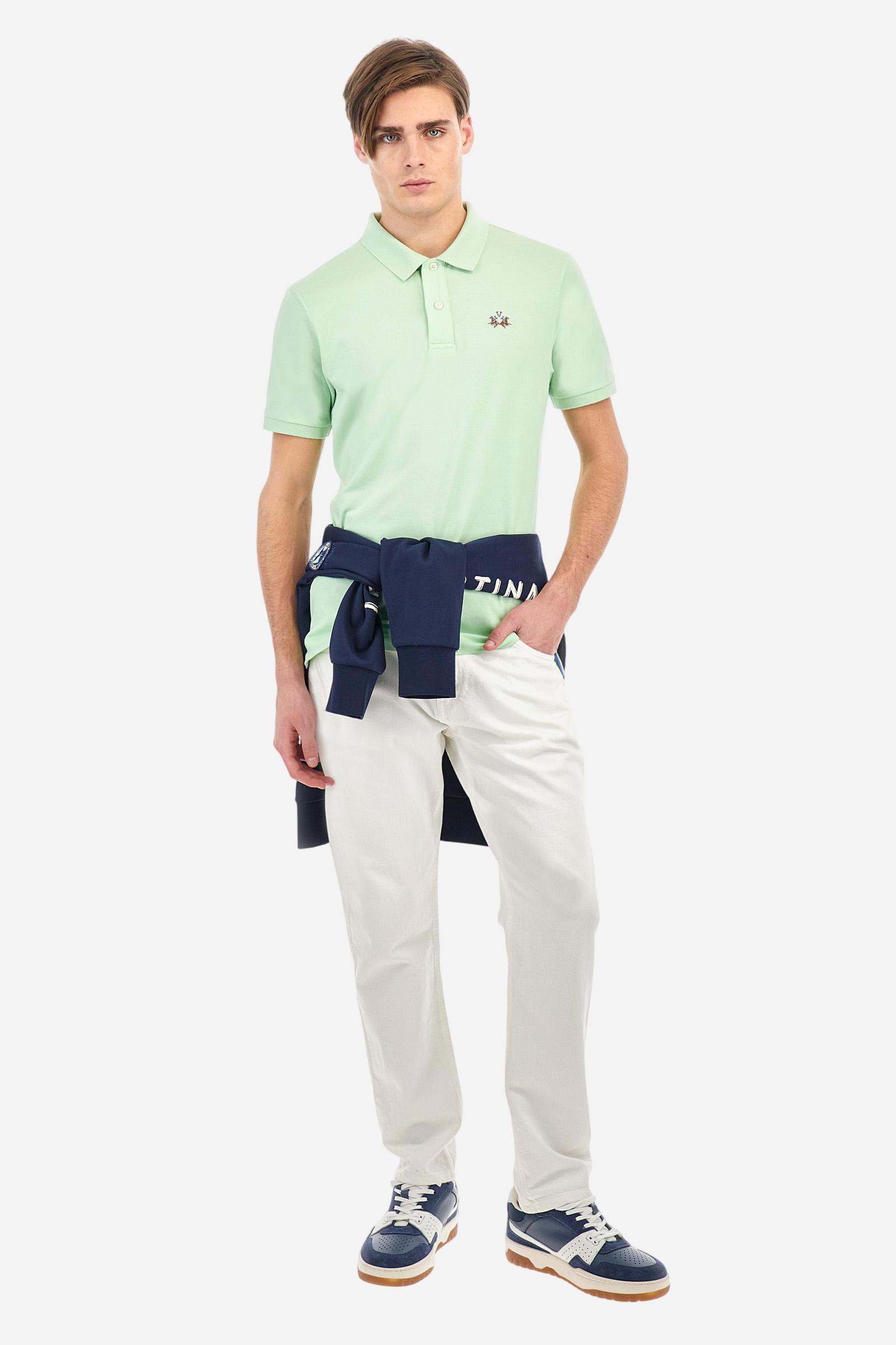 Men's plain short-sleeved polo shirt made from stretch piqué. Two-button fastening. The collar and cuffs are made from tone-on-tone ribbed fabric. Under the collar, there is a contrasting fabric panel with embroidered multicoloured lettering. The logo is embroidered on the left side of the chest in contrasting thread. Slim fit. The model is wearing a size L. - Pastel Green