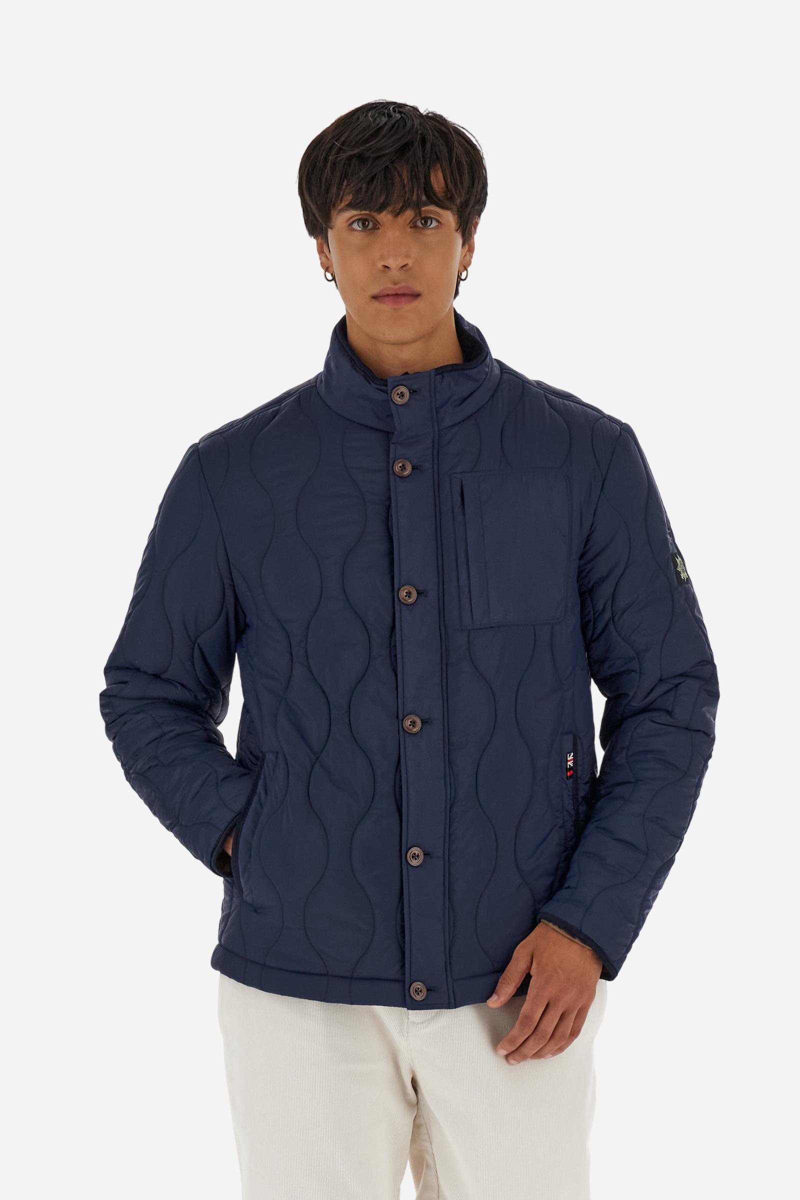 Men’s quilted nylon husky jacket with high collar. Front closure with customized zip and large faux-leather buttons. Interior lined with striped bicolor polyester. Contrast details on the inside (pockets, profiles, back-neck tab). Clean design with chest pocket closed by zip and vertical side pockets. Adjustable back straps with metal snap buttons. Logo patches on the sleeves and multicolor embroidered lettering on the outer collar. Part of the Guards capsule. Regular fit. Model wears size L. - Navy