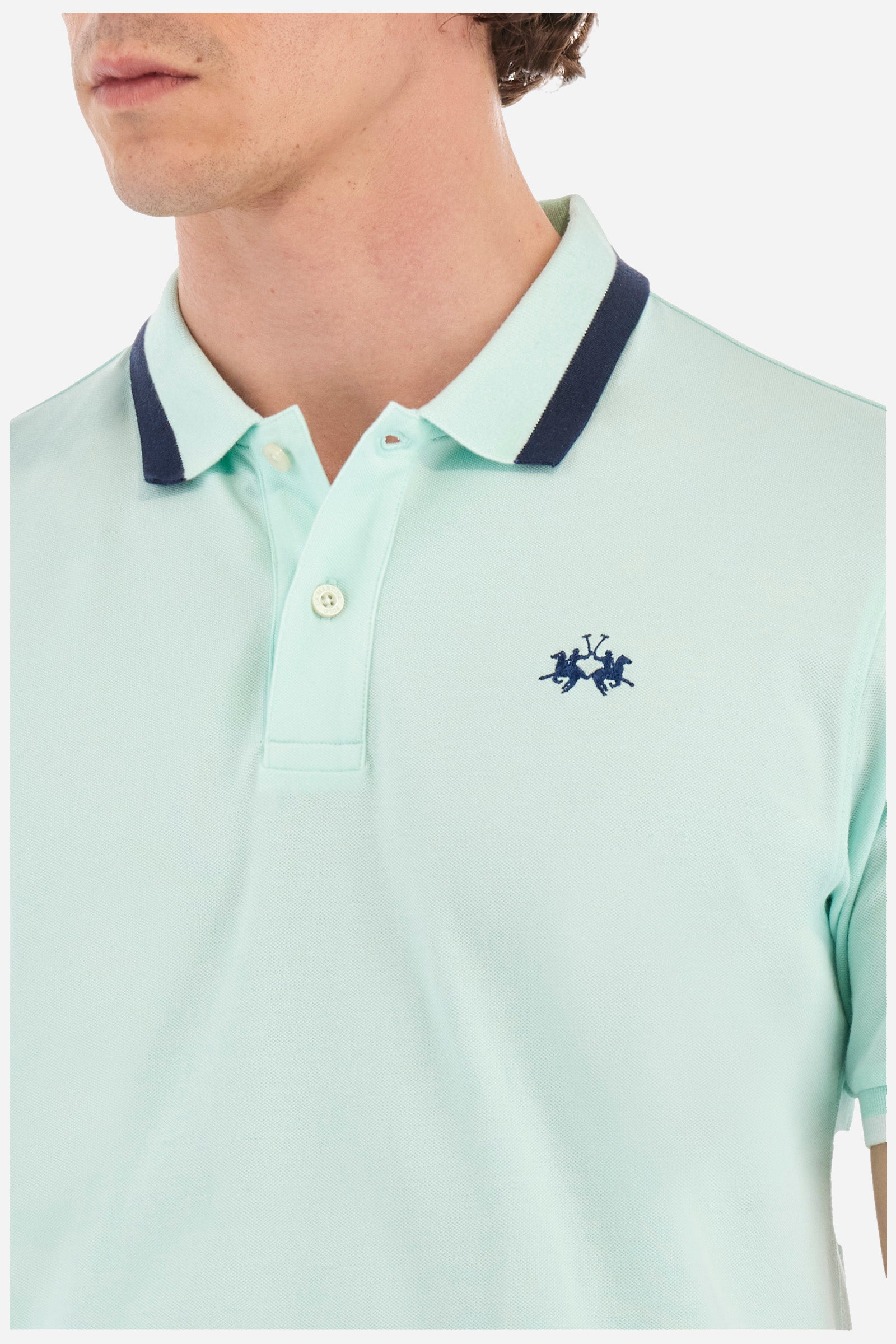 Men's single-colour short-sleeved polo in elasticated cotton. Two-button fastening. Ribbed collar and armholes with a stripe in different shades. The "La Martina" lettering can be found under the collar. Featuring a small logo embroidered on the chest. In a slim fit. The model wears a size L. - Honeydew
