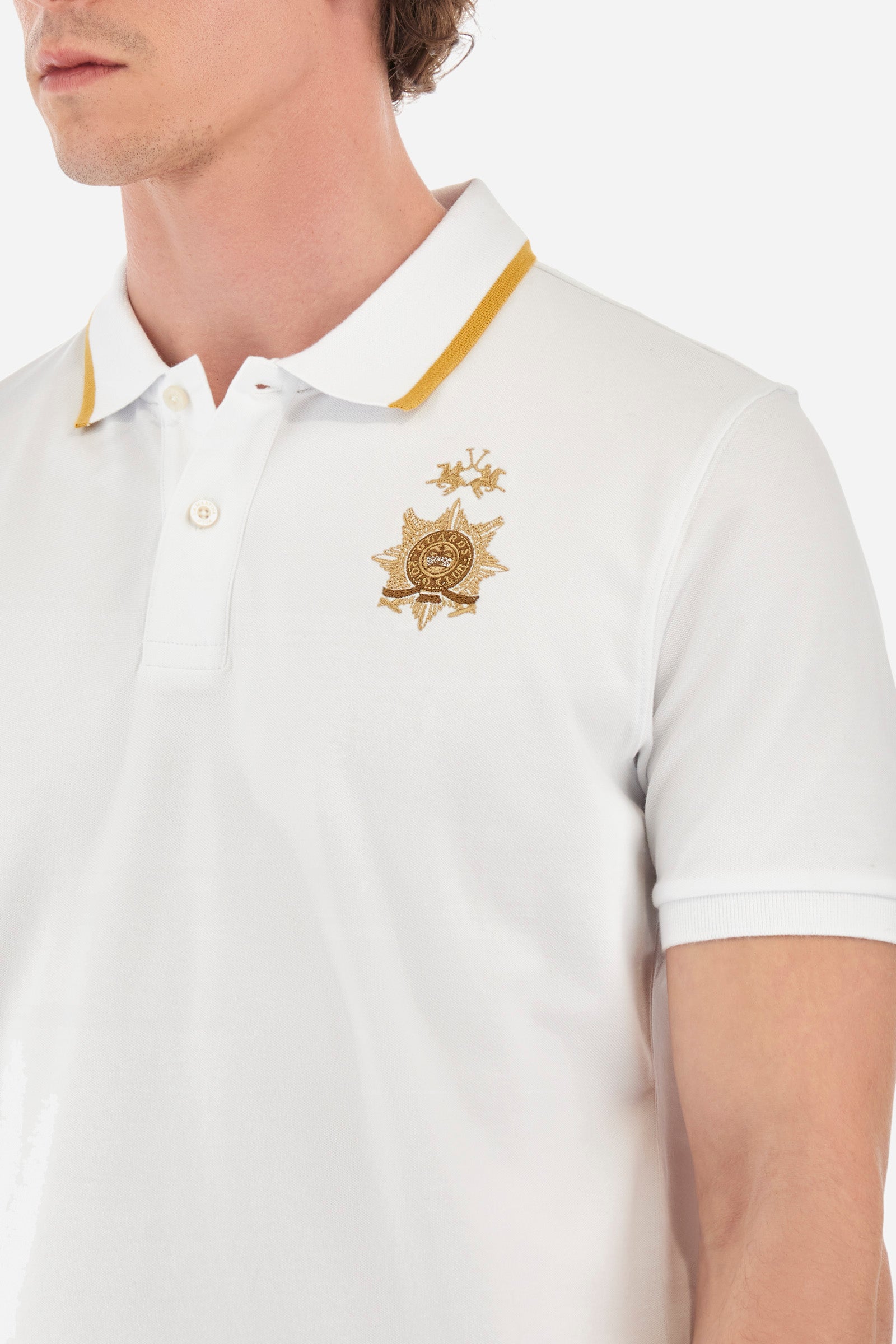 Men's short-sleeved single-colour polo shirt in elasticated cotton. Two-button fastening. Ribbed collar and armholes. The neck is profiled. On the front we find the symbol representing the Guards line. Featuring a small logo embroidered on the chest. The fit is regular. The model wears a size L. - Optic White